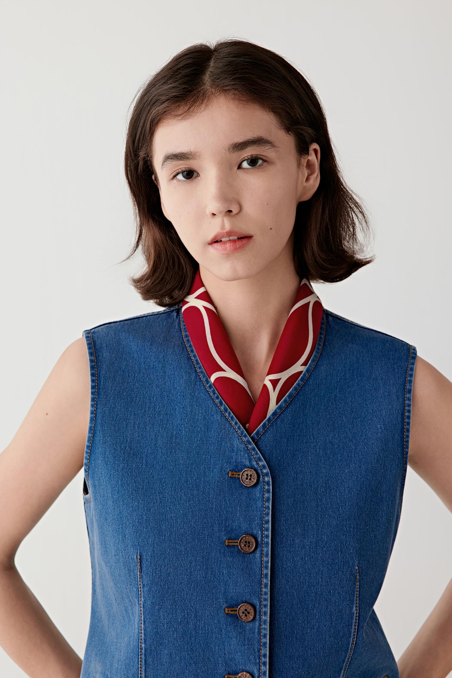 Three-quarter view showing the fitted shape through the torso, armhole cut and structured drape of the denim.