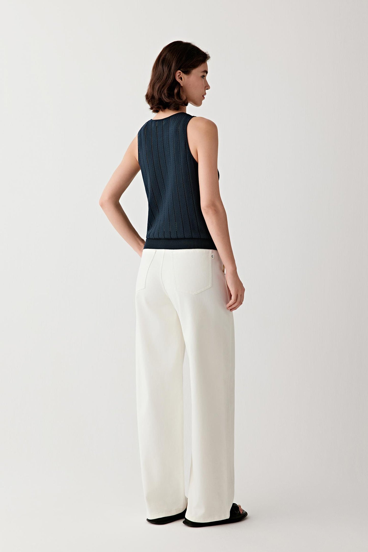 Side view highlighting the slim profile of the garment, the straight hemline and the way the knit fabric adapts to the body while maintaining a clean, continuous line