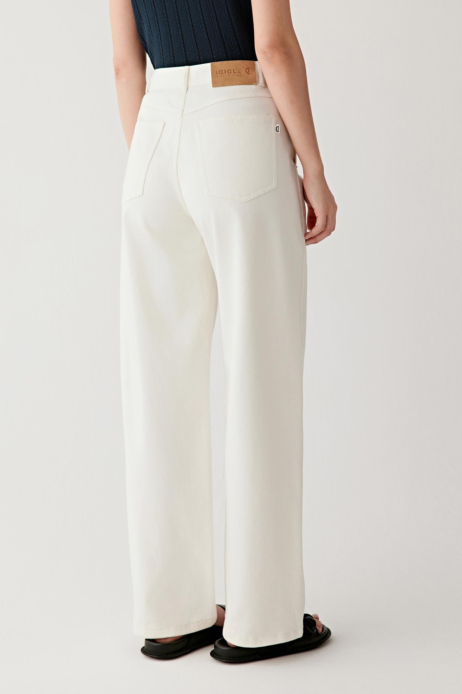 Side view showing the trousers in profile, highlighting the straight outer seam, the structured fall of the fabric and the way the denim maintains a clean, continuous line from waist to hem