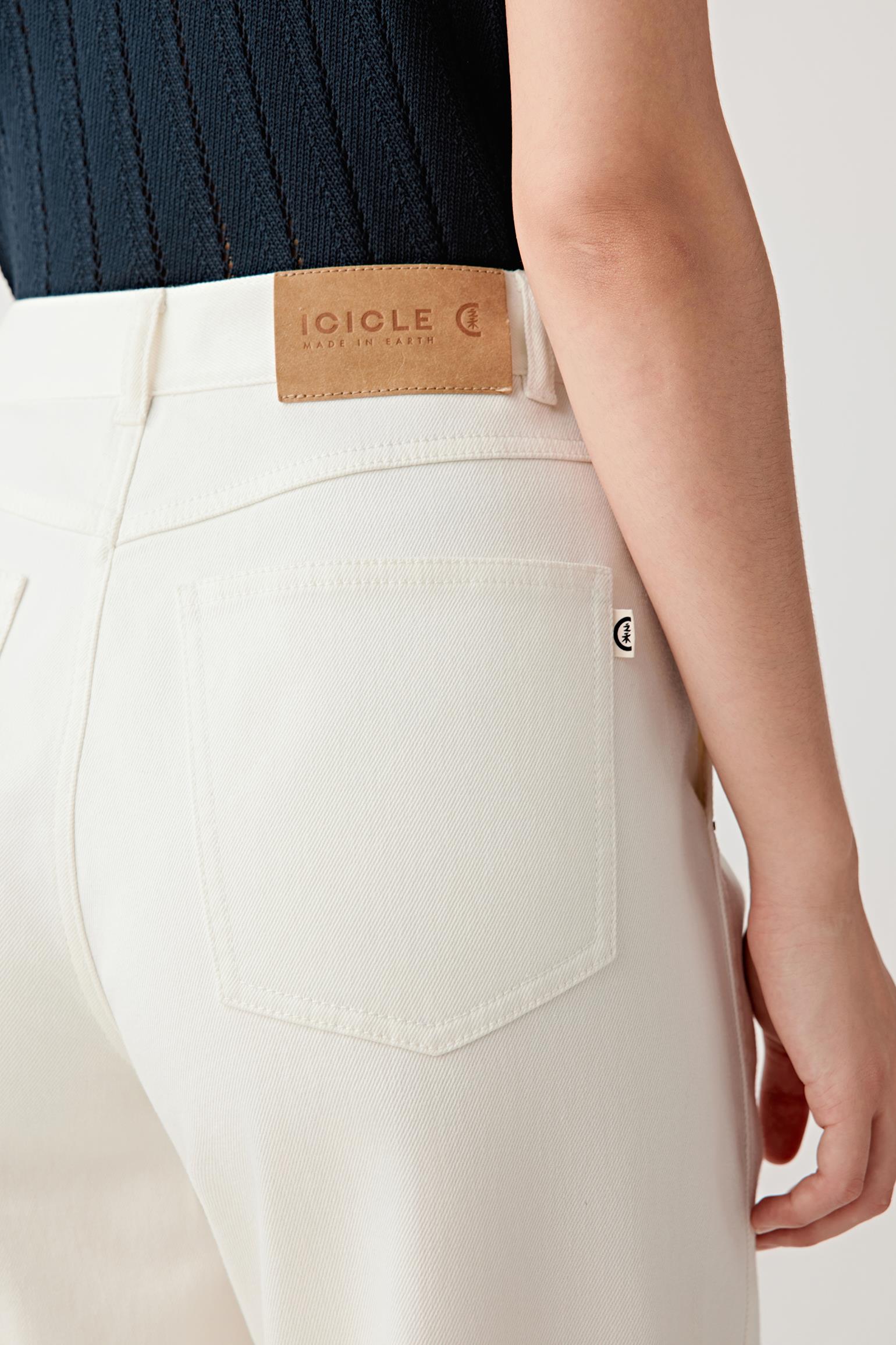 Close-up of the back waist and pocket area, showing the rear construction, pocket placement, seam lines and the natural, undyed denim surface with a matte, slightly grainy finish