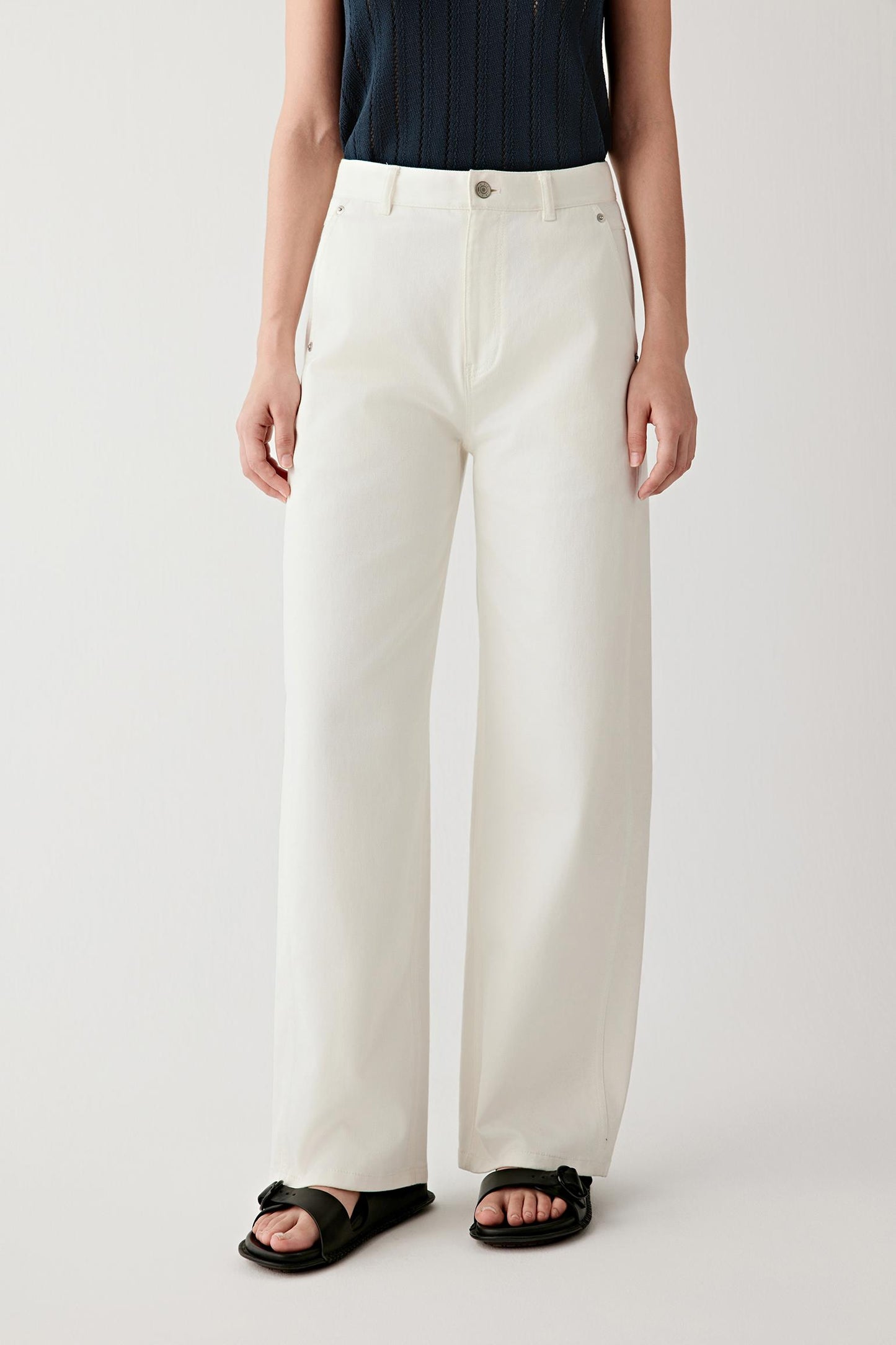Mid-length front view focusing on the trousers from waist to hem, emphasizing the straight-leg cut, the balanced volume through the leg and the smooth, lightly textured woven denim surface