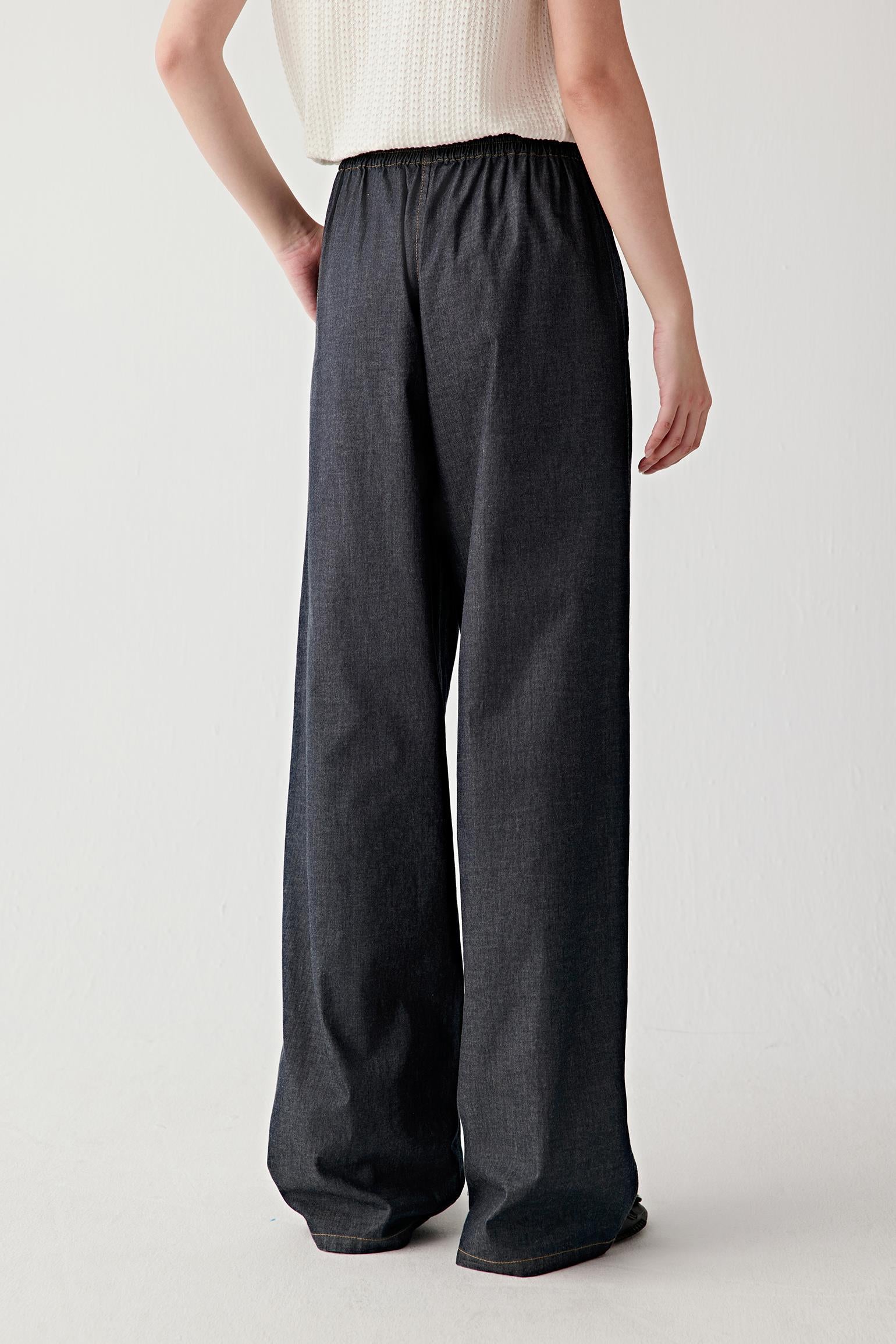 Side view showing the profile of the trousers, highlighting the volume through the leg, the straight outer seam line and the way the fabric moves with a soft, flexible drape
