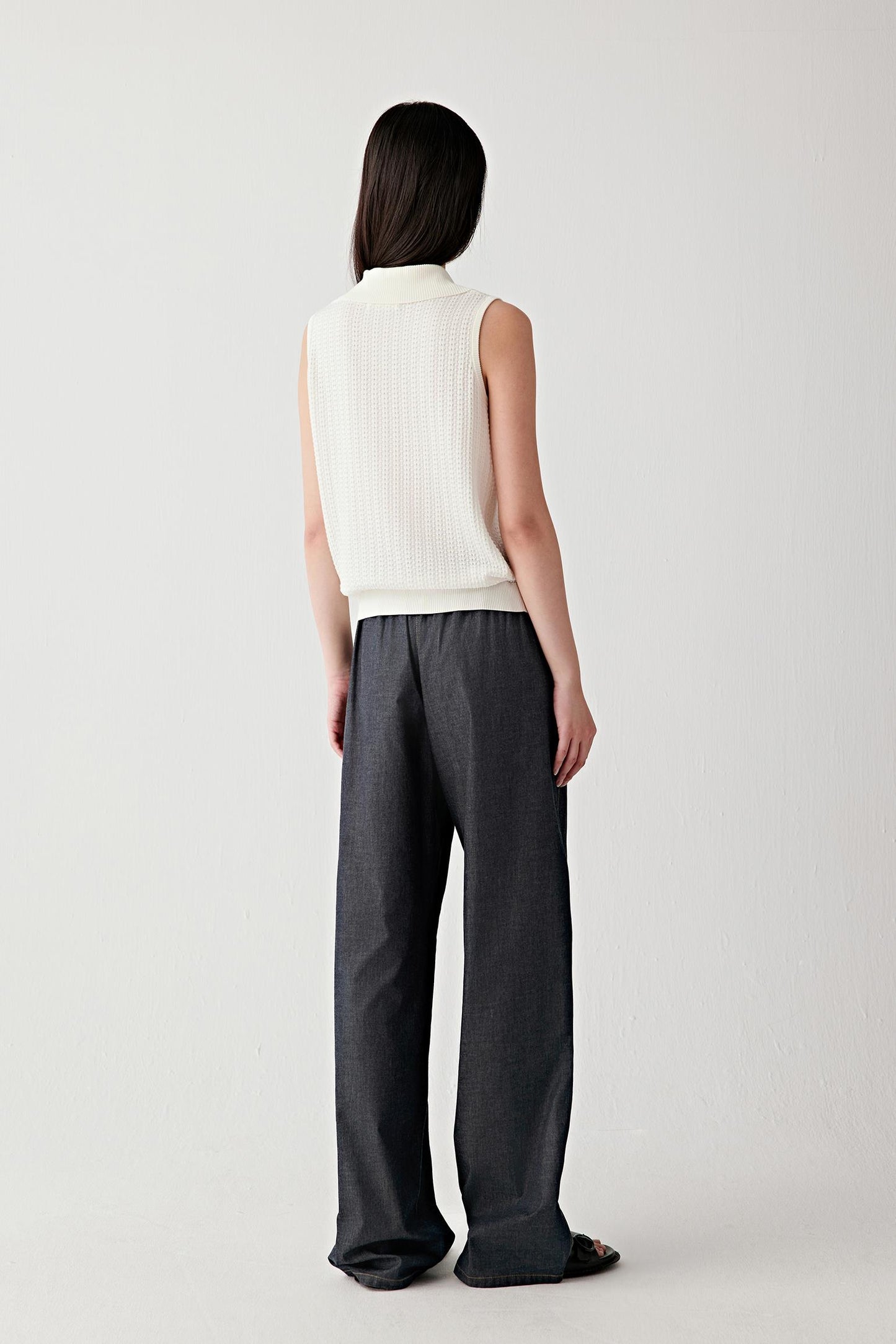 Full-length side view showing the garment in profile, highlighting the straight fall from shoulder to hem, the relaxed fit through the torso and the fluid yet softly structured drape of the cotton knit