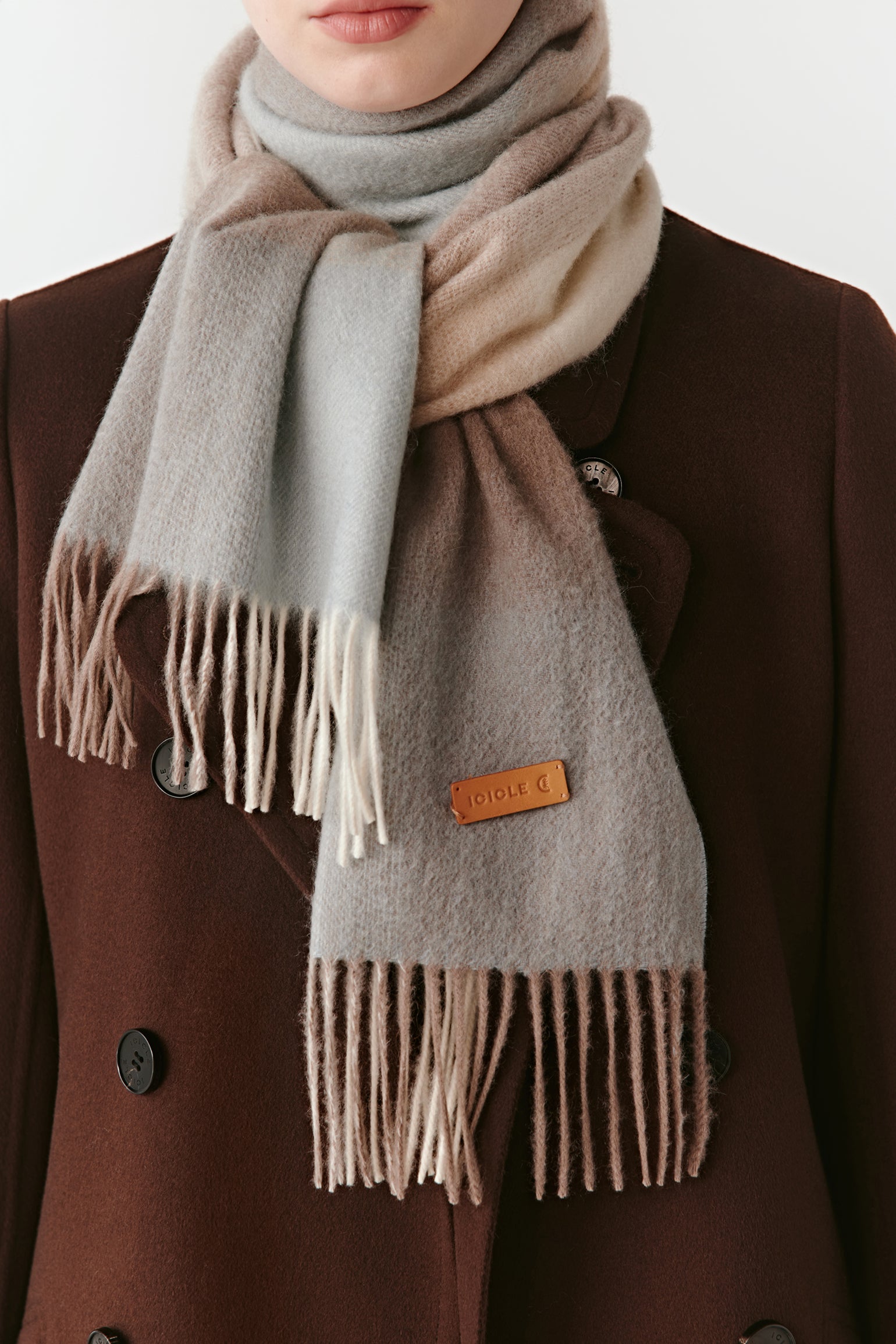 A close-up of the gradient cashmere scarf, showing the fine weave and soft fringed edges.