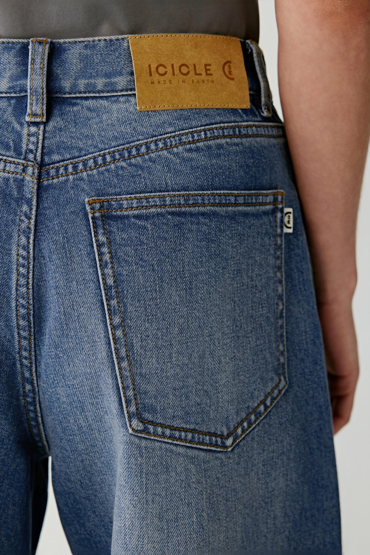 Close-up of the back showing the patch pocket, waistband label and washed blue denim finish.
