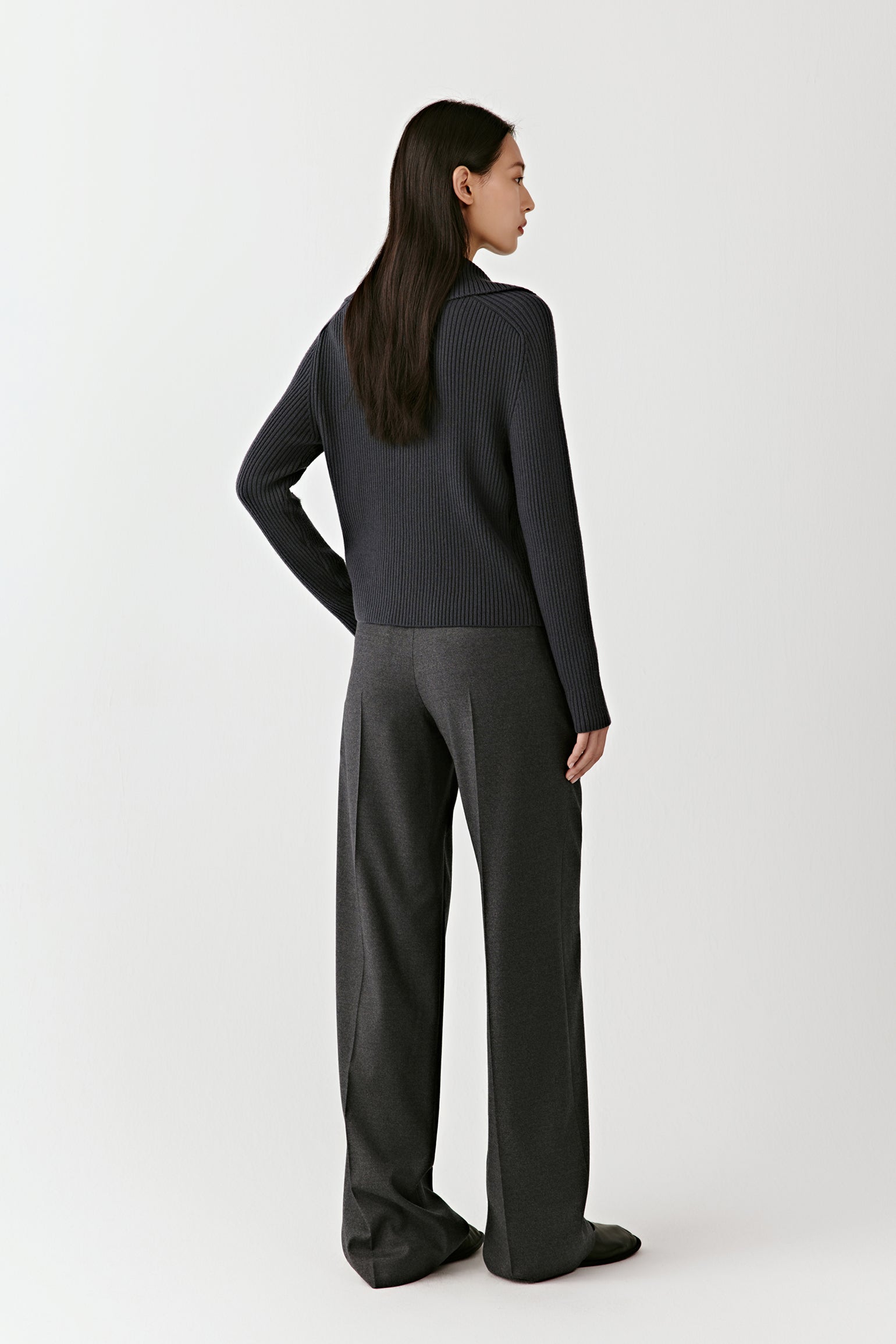 Back view of the blue ribbed wool cardigan, emphasizing the clean lines and tailored structure.