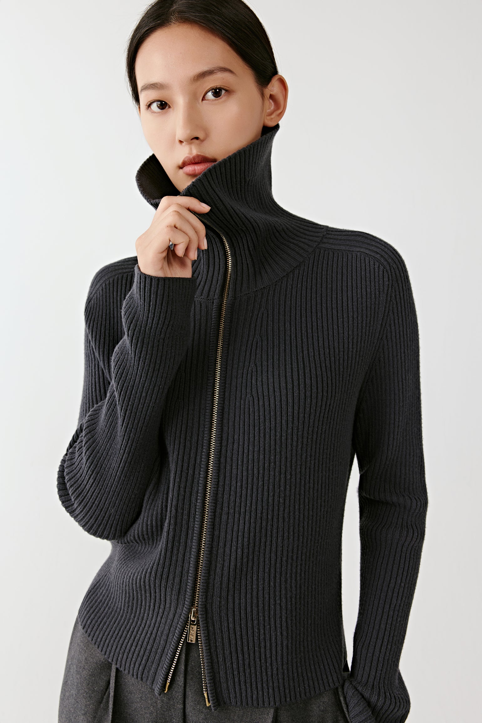 Three-quarter view of the cardigan zipped up, highlighting the funnel collar and ribbed texture.