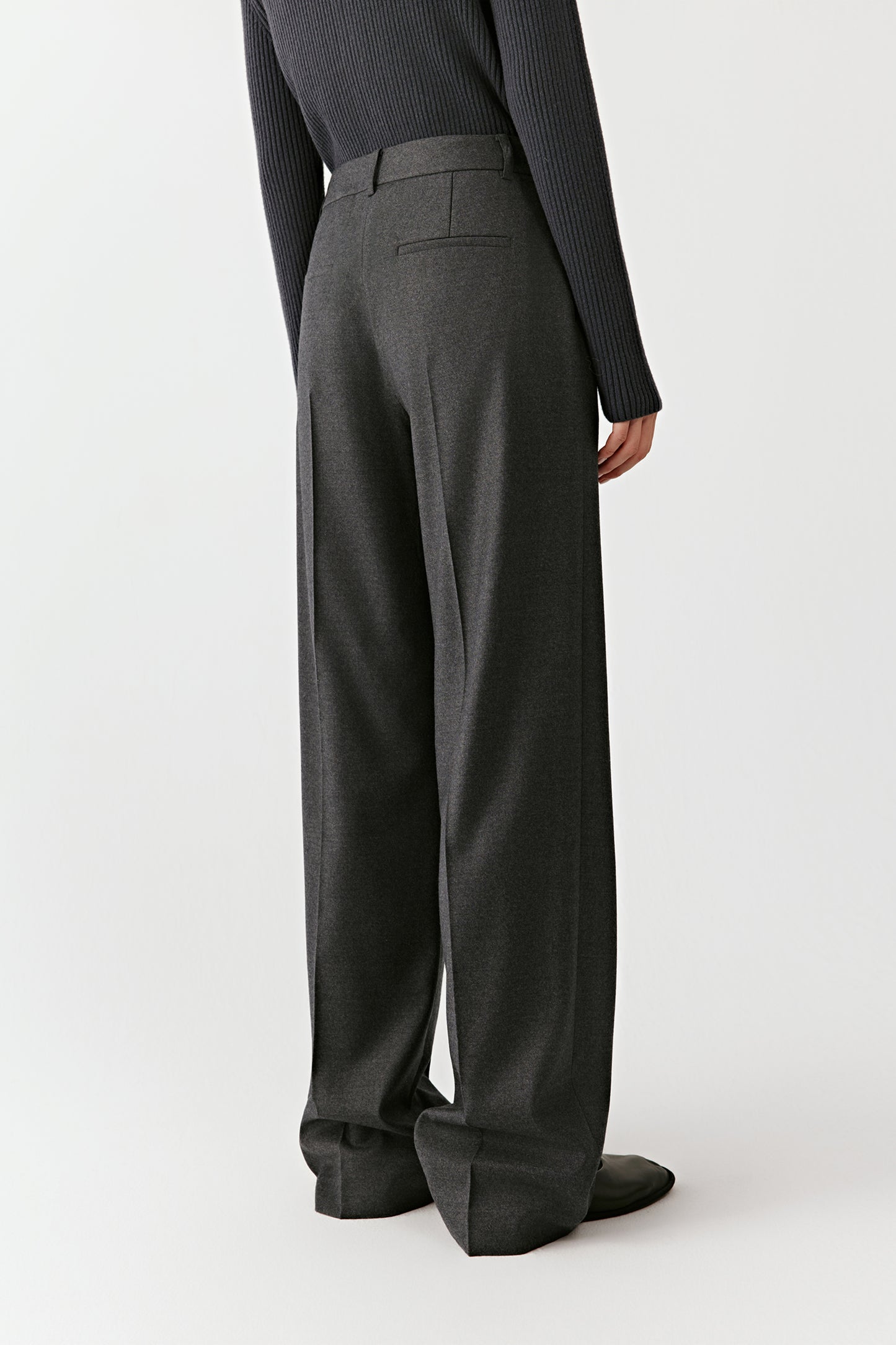 Back view of the grey trousers, highlighting the welt pockets and clean construction.