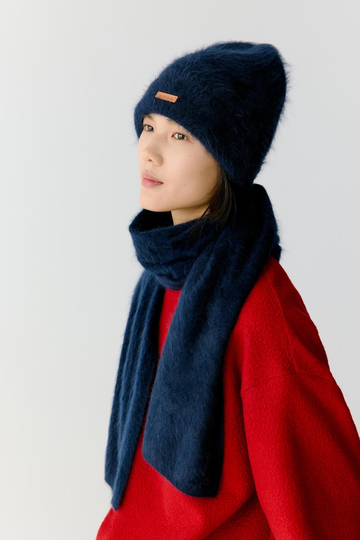 Three-quarter view showing the scarf wrapped around the neck and falling vertically through the front of the body. The lightweight cashmere forms soft folds and natural volume, demonstrating its supple hand and comfortable, enveloping character.