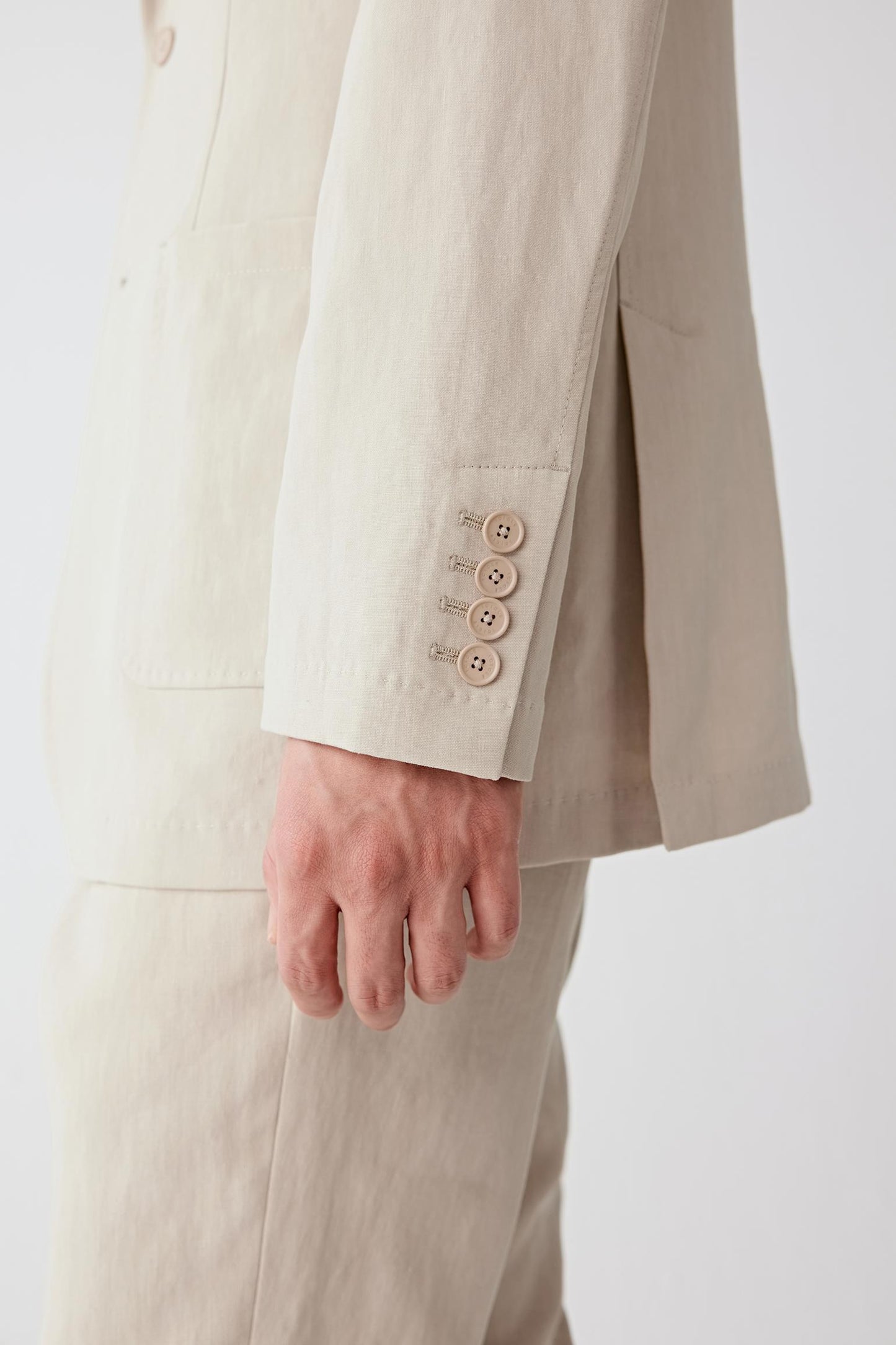 Close-up of the sleeve and cuff, highlighting seam construction, clean finishing and the slightly dry, structured hand of the fabric, with subtle variations in tone emphasizing the natural character of the linen