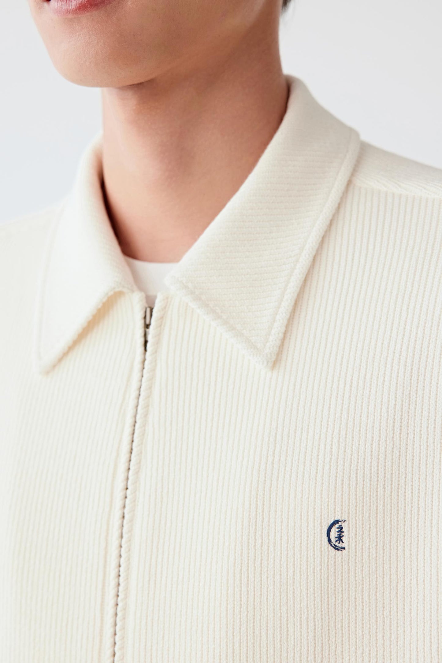 Close-up of the collar and zip, revealing refined construction and understated finishing.