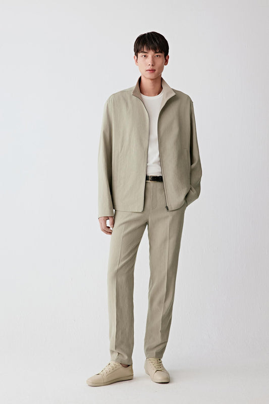 Full-length front view of a man standing facing forward wearing a beige linen jacket paired with matching trousers, highlighting the straight silhouette, clean proportions and lightweight structure, with a softly textured surface and subtle irregularities characteristic of plain-woven linen