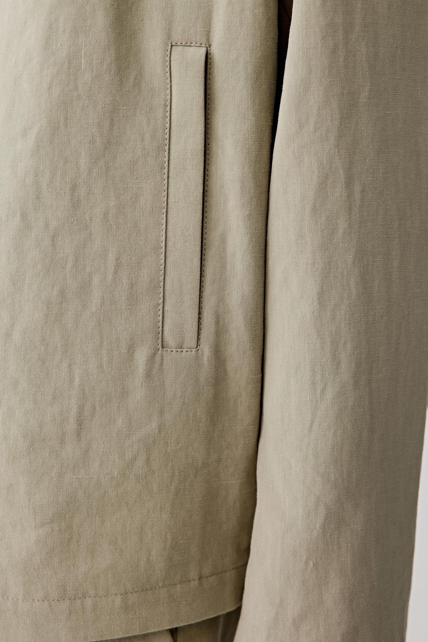 Close-up of the fabric and lower body area, emphasizing the vertical pockets, stitching details and the lightly textured surface, with visible weave irregularities enhancing the natural character of the linen