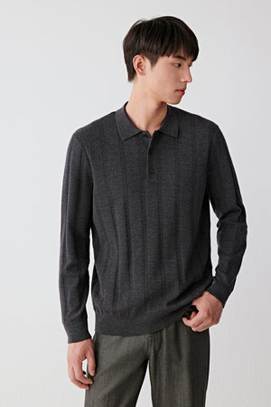Man wearing a black merino wool knit pullover with relaxed fit and ribbed buttoned collar, styled with dark trousers, three-quarter portrait view.