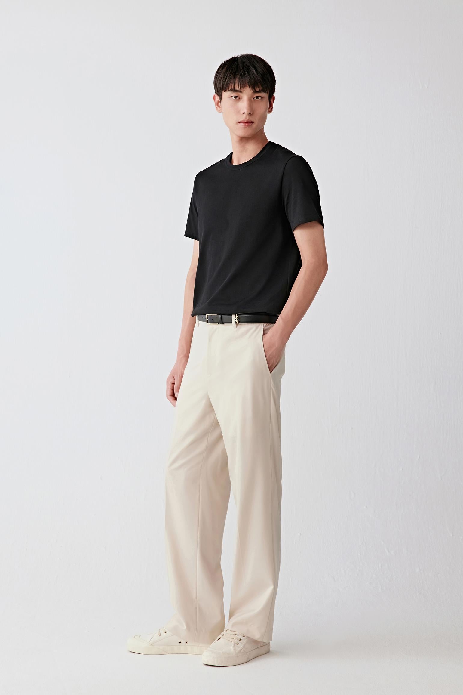 Full-length front view of men’s beige wool trousers with a relaxed straight leg, styled with a black T-shirt.