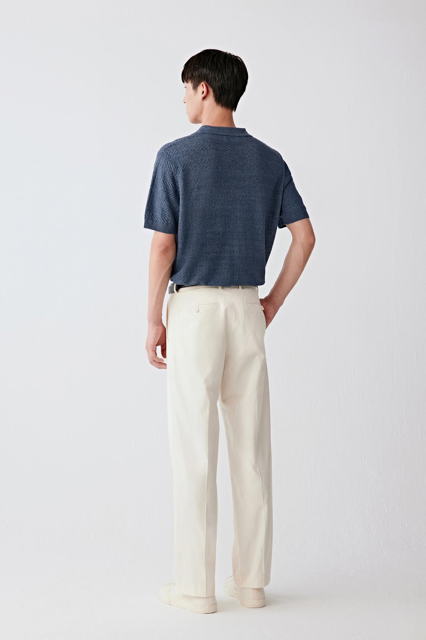 Full-length back view highlighting the rear silhouette, with a straight cut through the body, relaxed shoulders and a continuous drape, while the fabric maintains a slightly structured yet airy feel