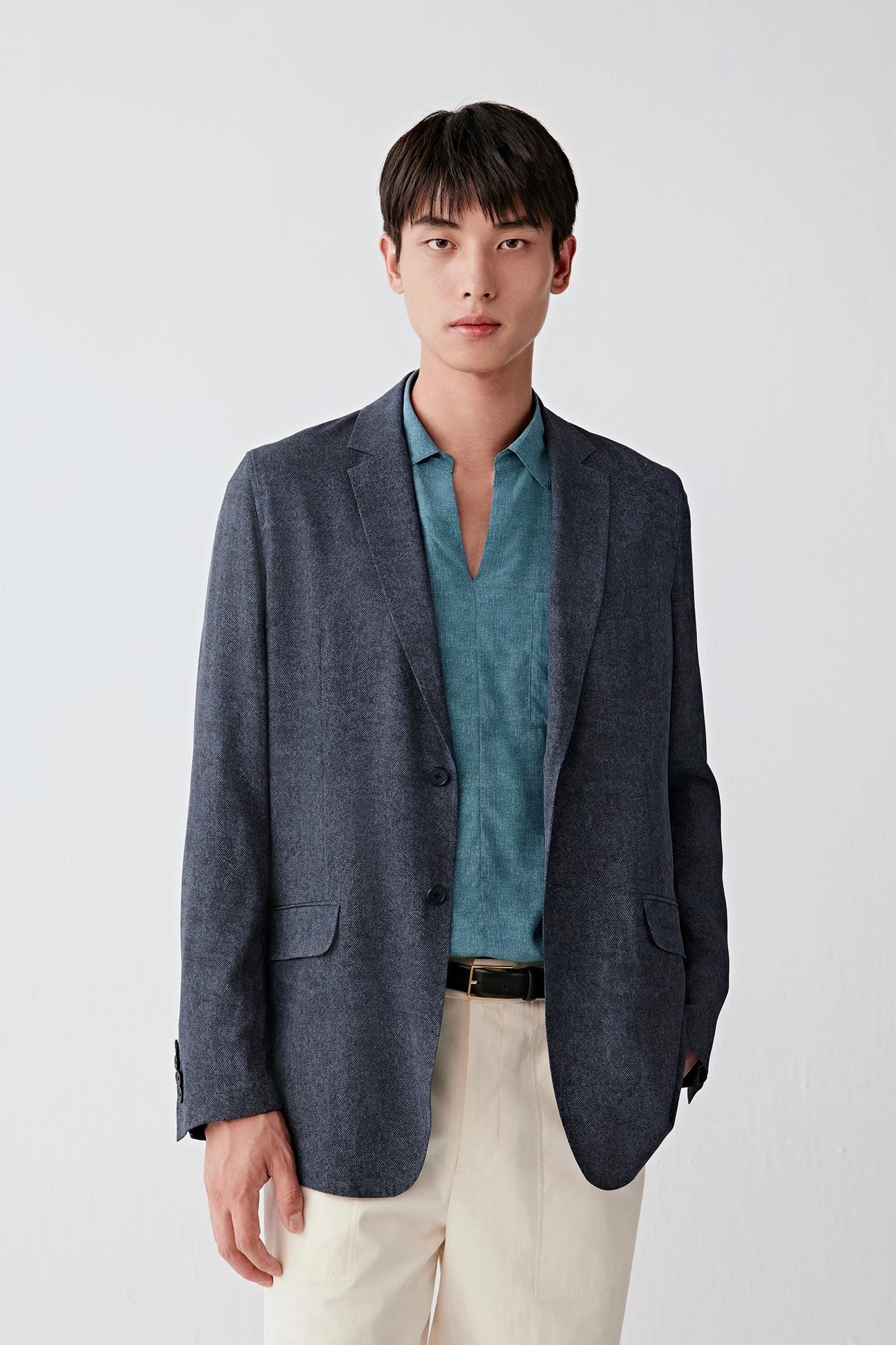 Three-quarter front view focusing on the upper body, emphasizing the classic lapel, single-breasted closure and balanced proportions, with the indigo tone revealing slight tonal variation across the silk twill surface