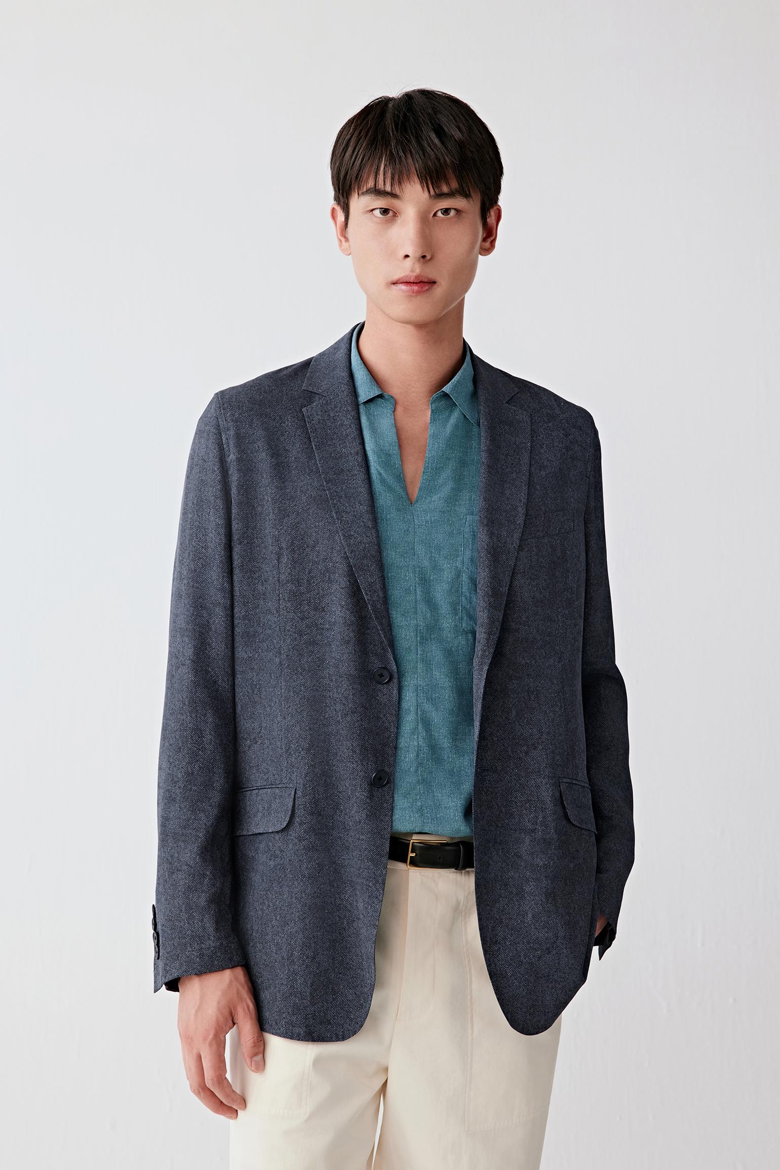 Three-quarter front view focusing on the upper body, emphasizing the classic lapel, single-breasted closure and balanced proportions, with the indigo tone revealing slight tonal variation across the silk twill surface