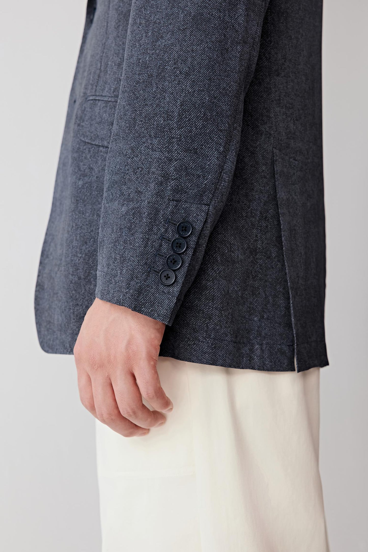 Close-up of the sleeve and cuff, highlighting the clean finishing, seam construction and the soft drape of the fabric, with the indigo shade showing subtle depth and light reflection along the weave