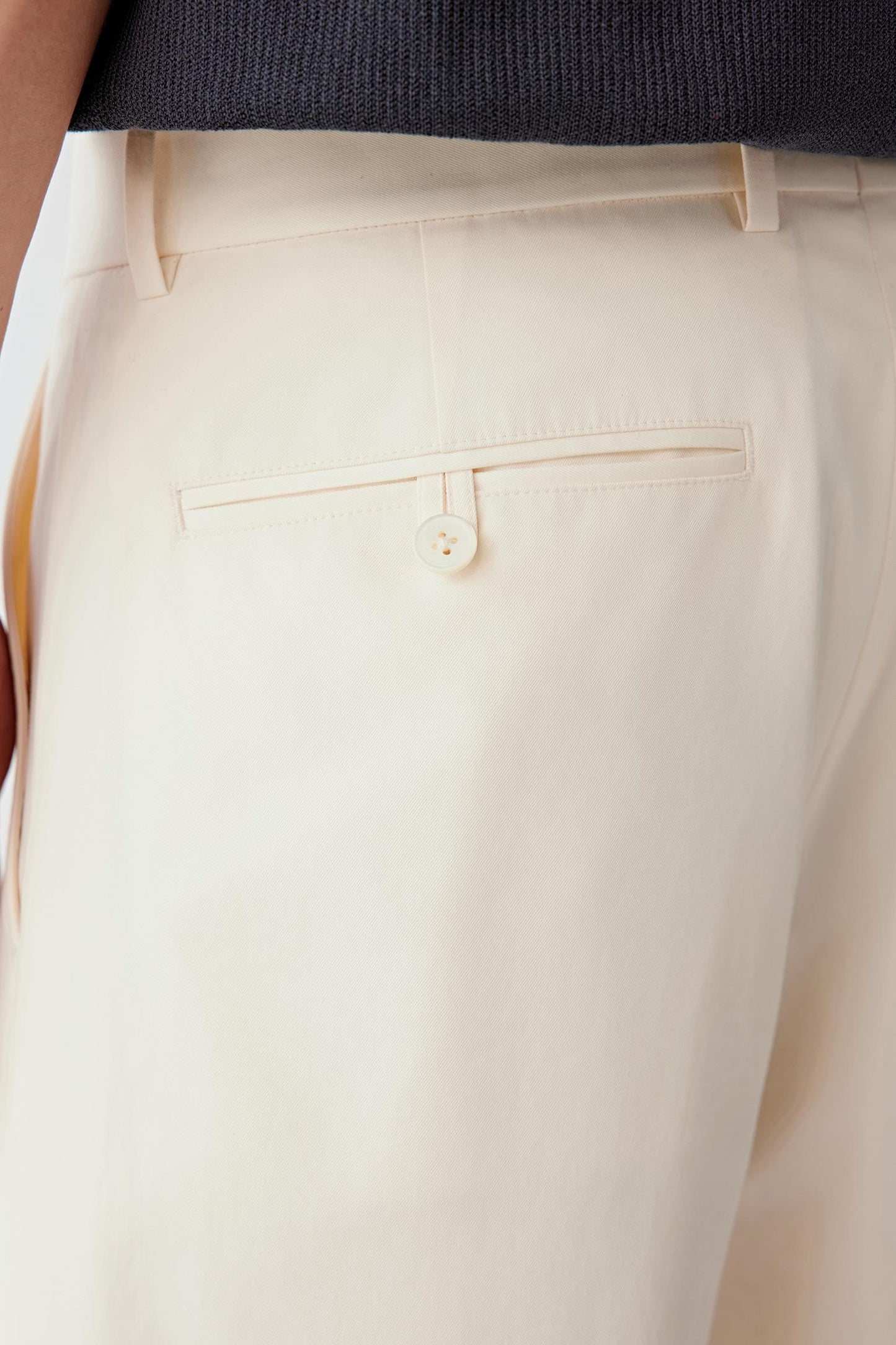 Close-up of the back pocket and waistband, highlighting the clean finishing, pocket placement and the compact structure of the fabric, with the light beige shade emphasizing the even texture and refined surface