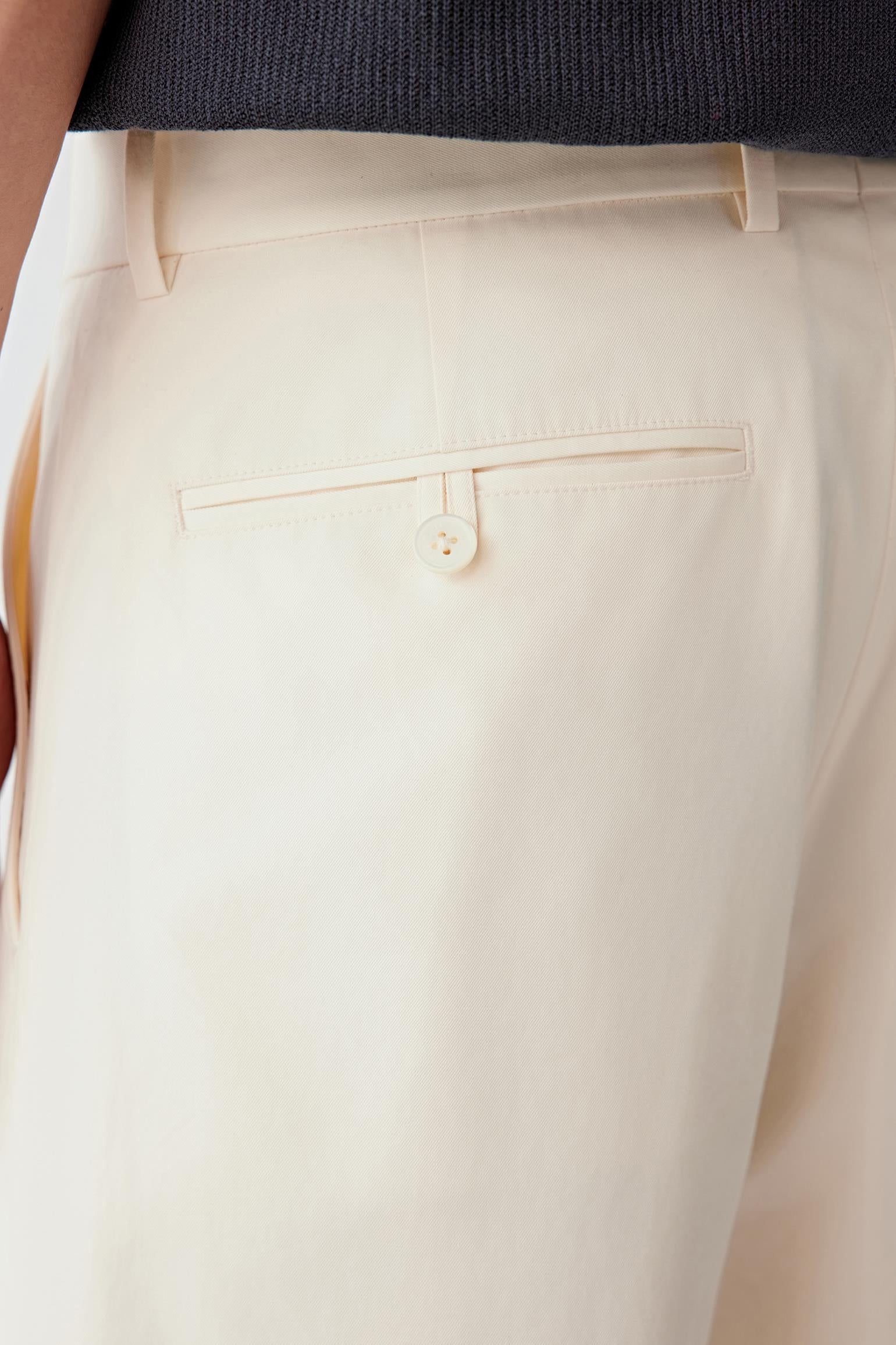 Close-up of the back pocket and waistband, highlighting the clean finishing, pocket placement and the compact structure of the fabric, with the light beige shade emphasizing the even texture and refined surface
