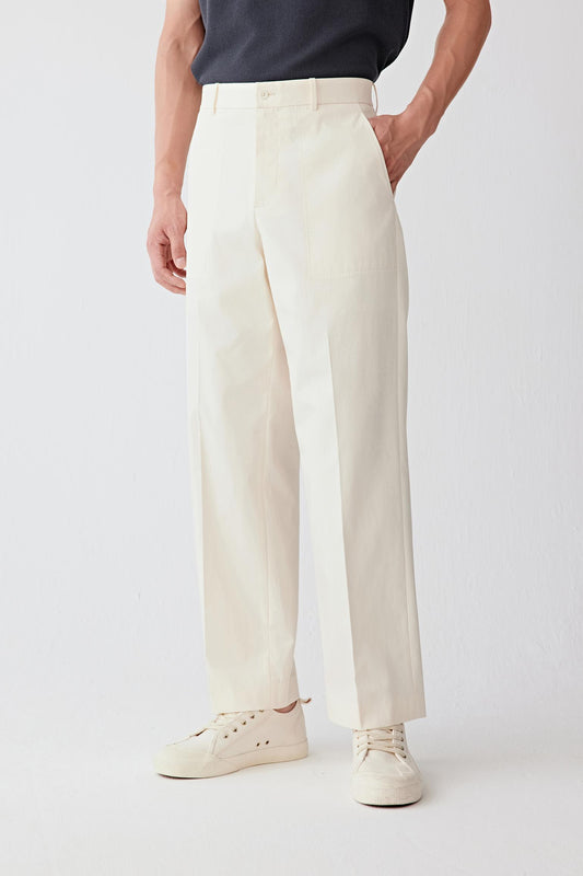 Mid-length front view focusing on the waist and upper leg, emphasizing the clean waistband, precise finishing and the structured fall of the fabric, with the light beige tone revealing subtle depth and a uniform surface
