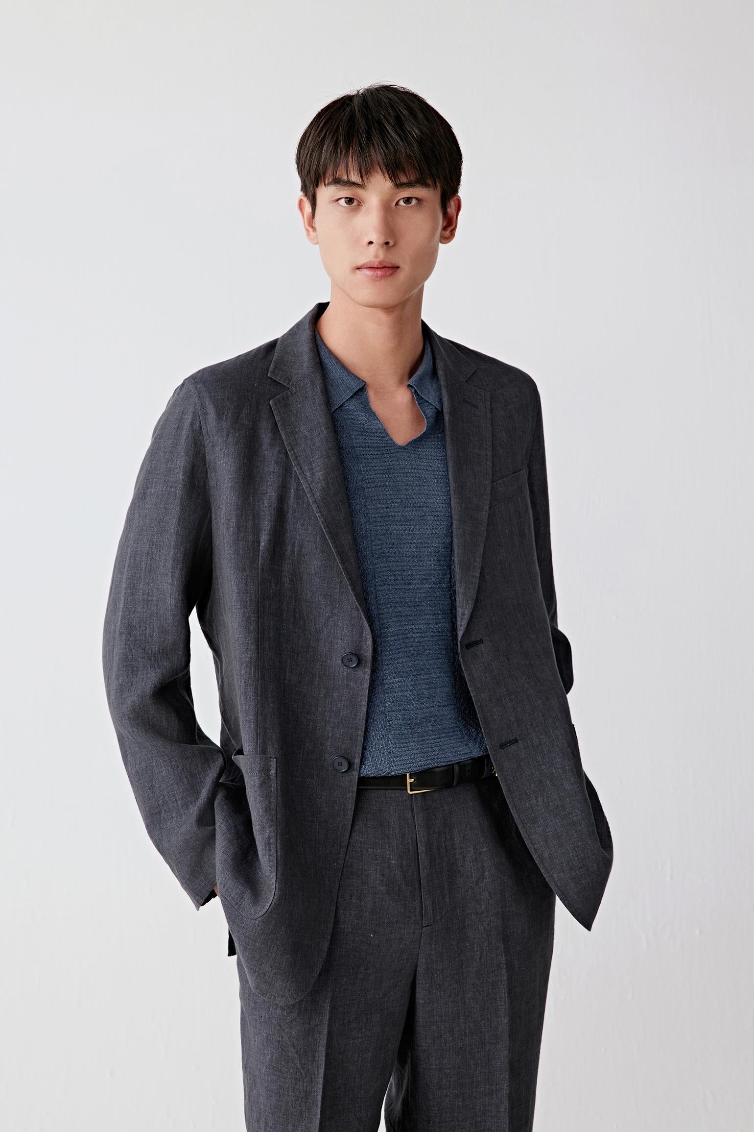 Three-quarter front view focusing on the upper body, emphasizing the open front, clean lapel construction and patch pockets, with the deep blue tone revealing slight tonal variation and the natural grain of the linen