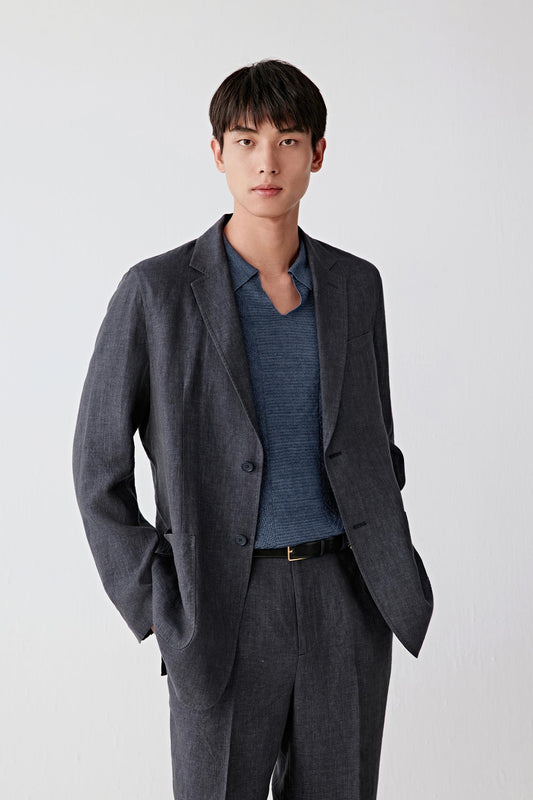 Three-quarter front view focusing on the upper body, emphasizing the open front, clean lapel construction and patch pockets, with the deep blue tone revealing slight tonal variation and the natural grain of the linen