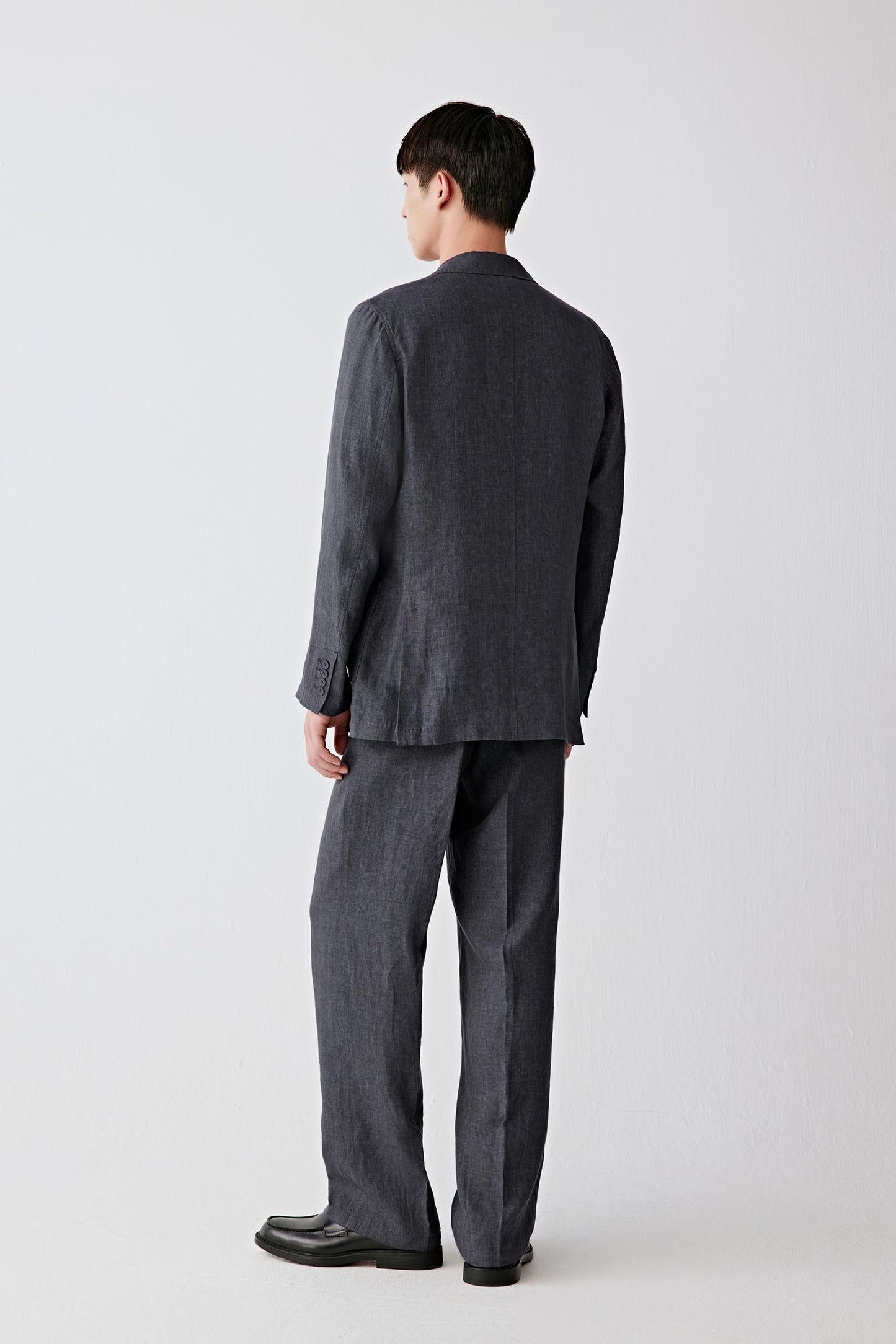 Full-length back view showing the rear silhouette, highlighting the clean shoulder line, straight cut and continuous fall from collar to hem, with the fabric maintaining a lightweight, breathable structure