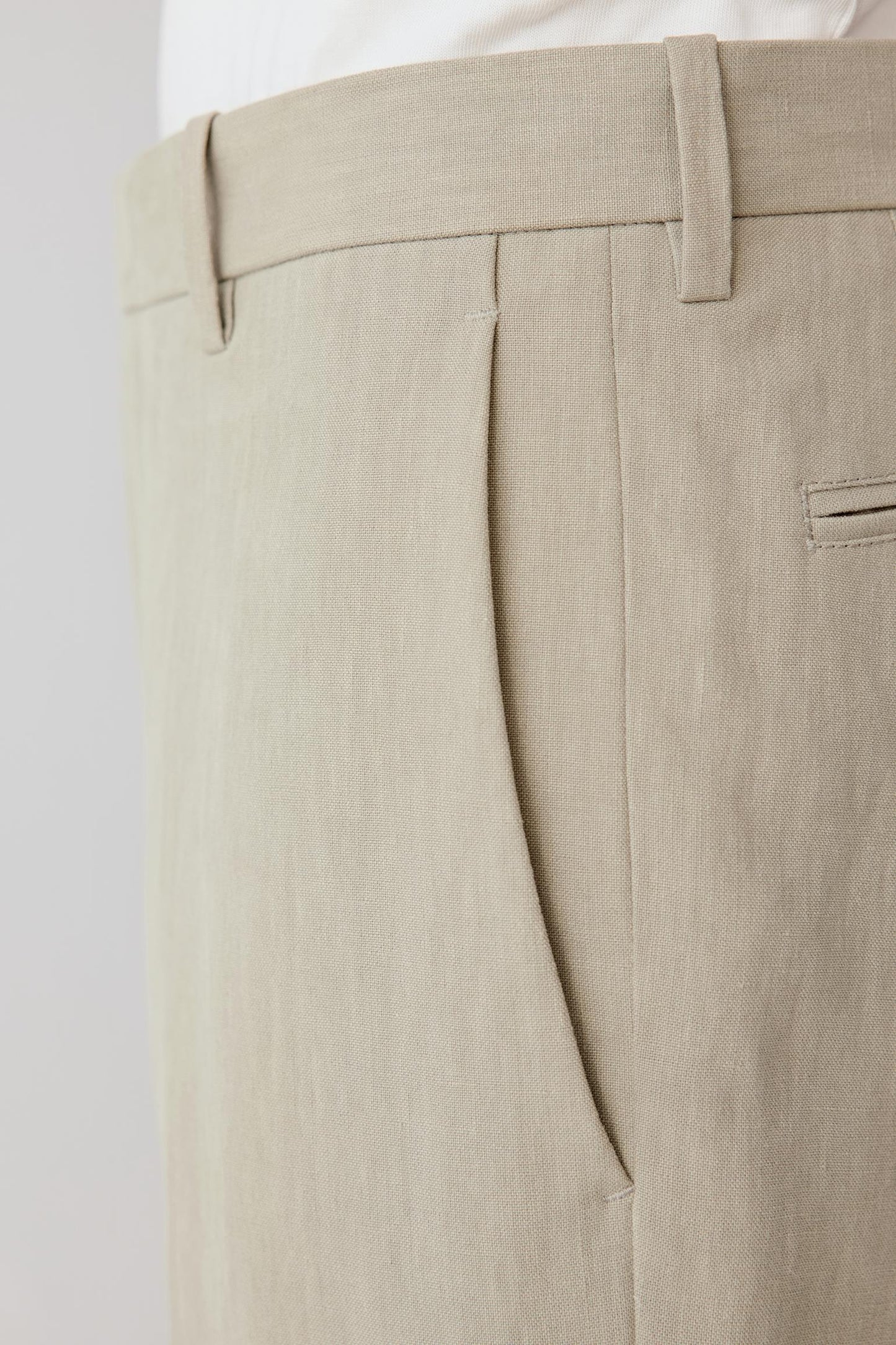 Close-up of the waistband and pocket showing the discreet pocket construction, stitching and subtly irregular linen texture.