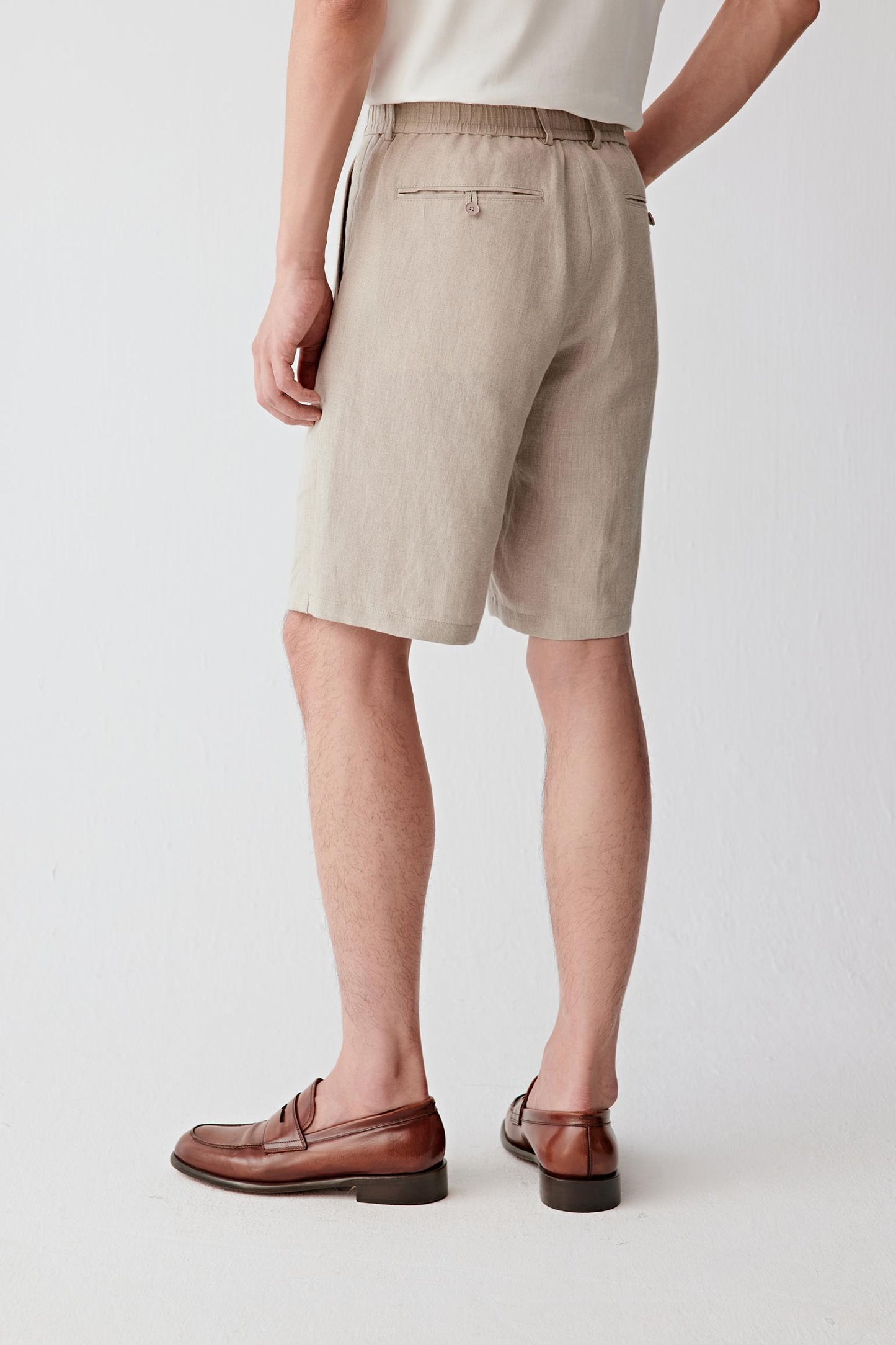 Side view highlighting the straight leg, lightweight drape and natural movement of the linen fabric. The clean side seam and precise construction contribute to the refined appearance of the garment.