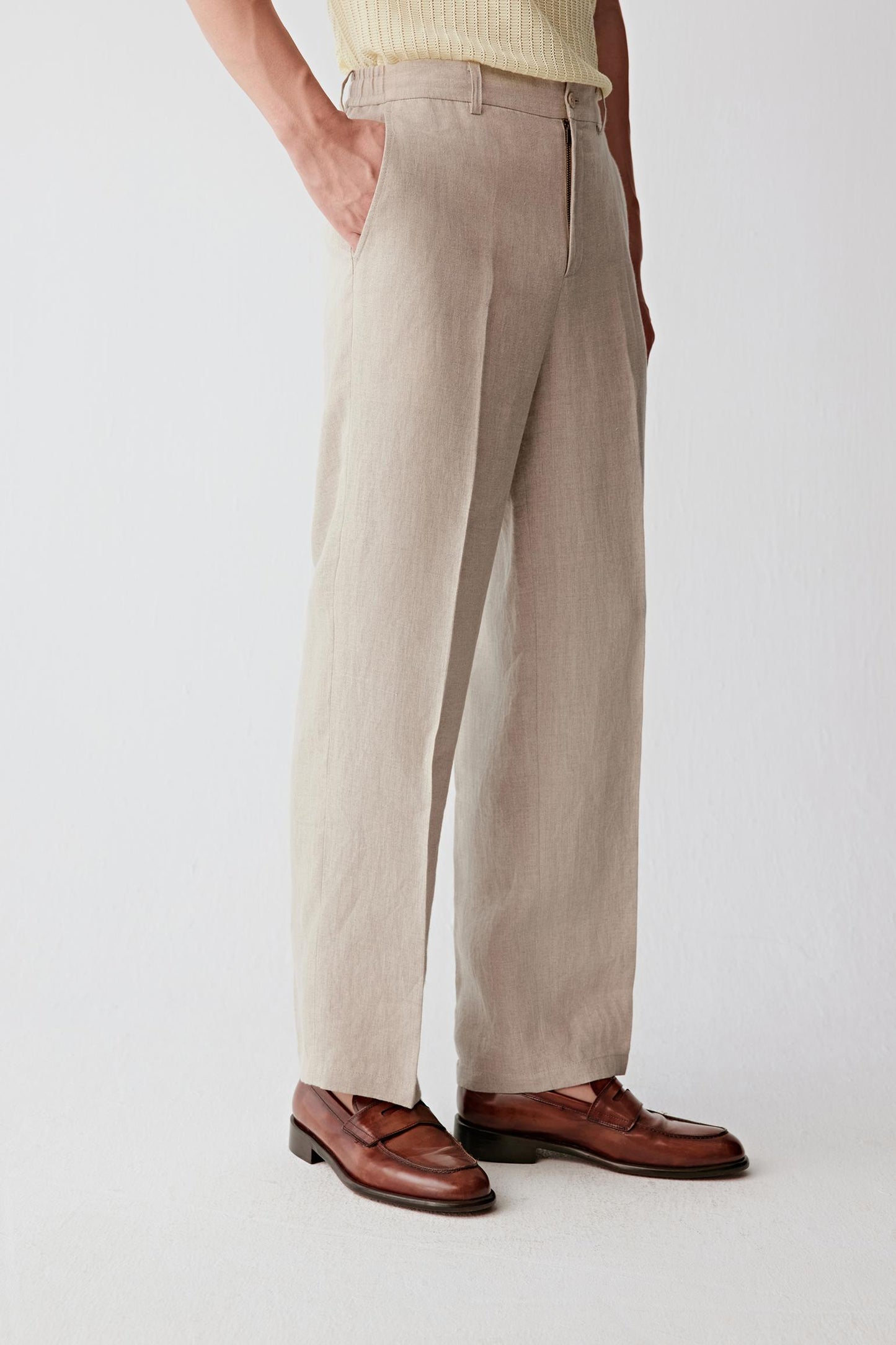 Side view focusing on the clean line of the leg and the fluid drape of the linen fabric. The image emphasizes the balanced proportions, lightweight construction and relaxed elegance of the straight-cut silhouette.