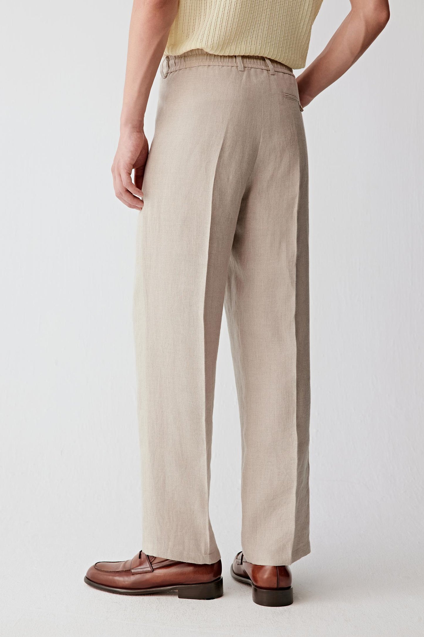 Back view highlighting the clean structure of the trousers, the straight-leg cut and the natural movement of the linen fabric. The lightweight weave falls smoothly while maintaining subtle texture and shape.