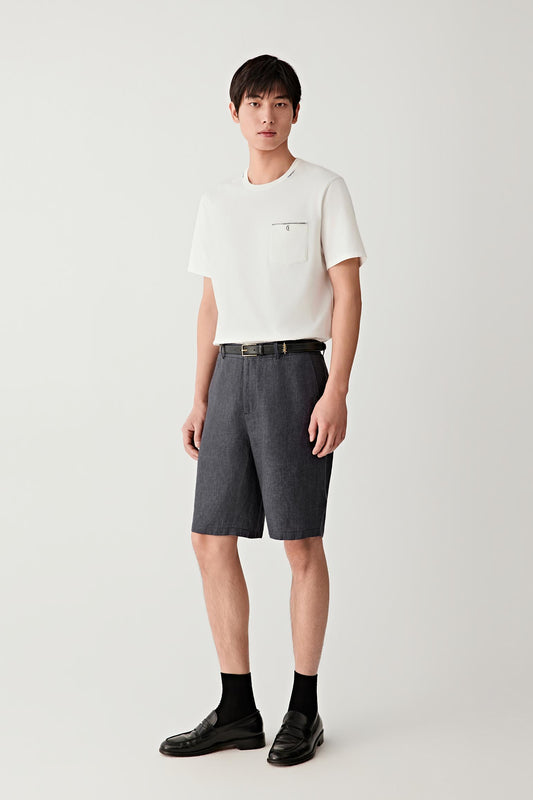 Full-length front view of a man standing facing forward wearing blue-black linen shorts paired with a white T-shirt, highlighting the straight, above-the-knee cut, clean lines and lightweight structure, with a dry hand feel and subtly textured surface characteristic of plain-woven linen