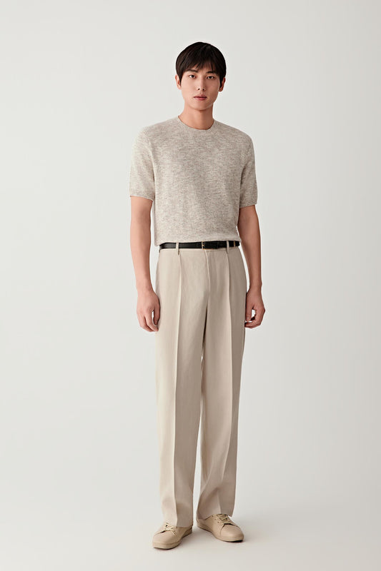 Full-length front view of a beige short-sleeve cotton and silk knit pullover paired with light trousers.