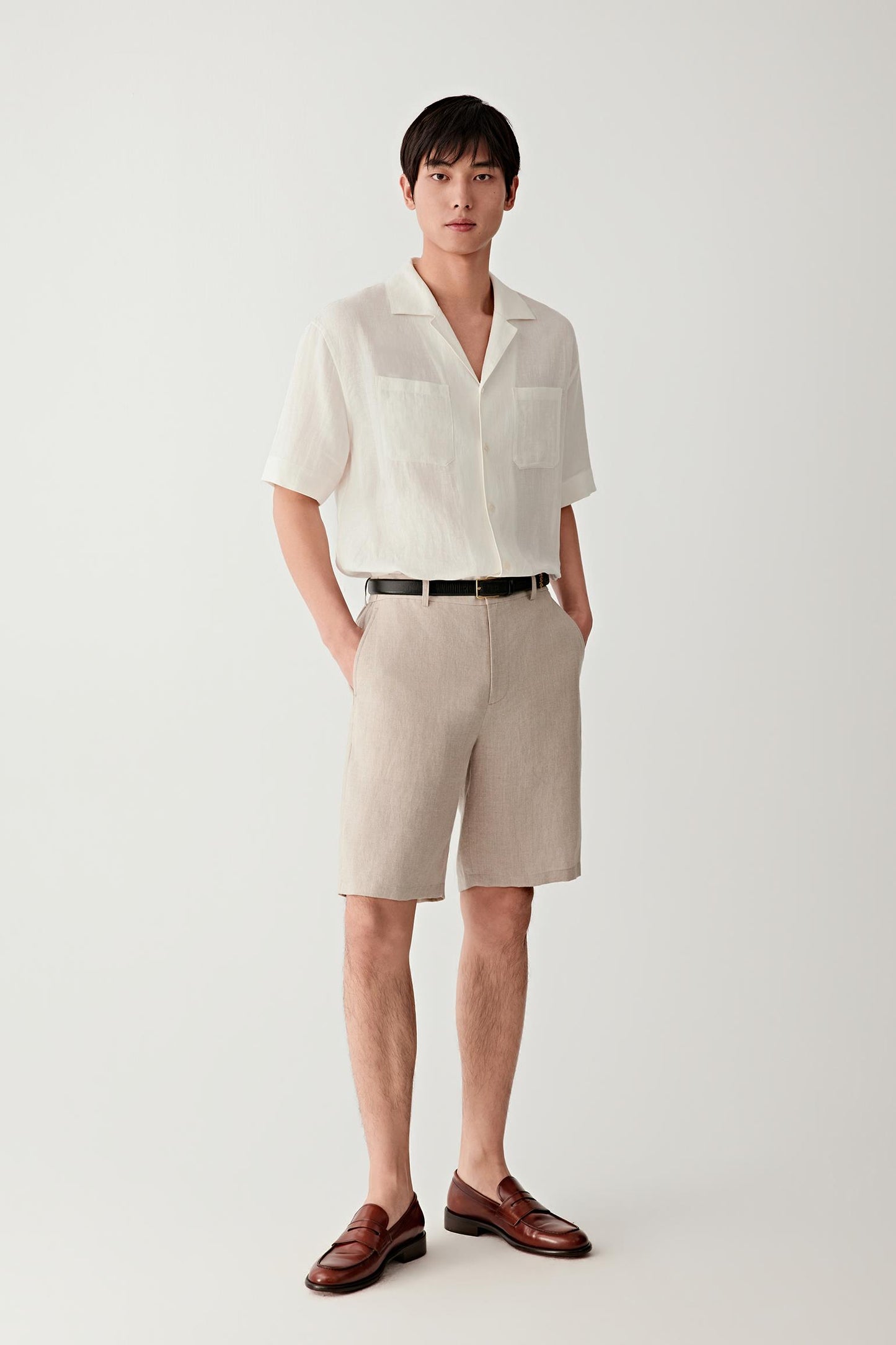 Full-length view showing the shirt paired with coordinating shorts. The image emphasizes the fluid drape, open collar construction and easy proportions of the garment, illustrating its relaxed warm-weather character.