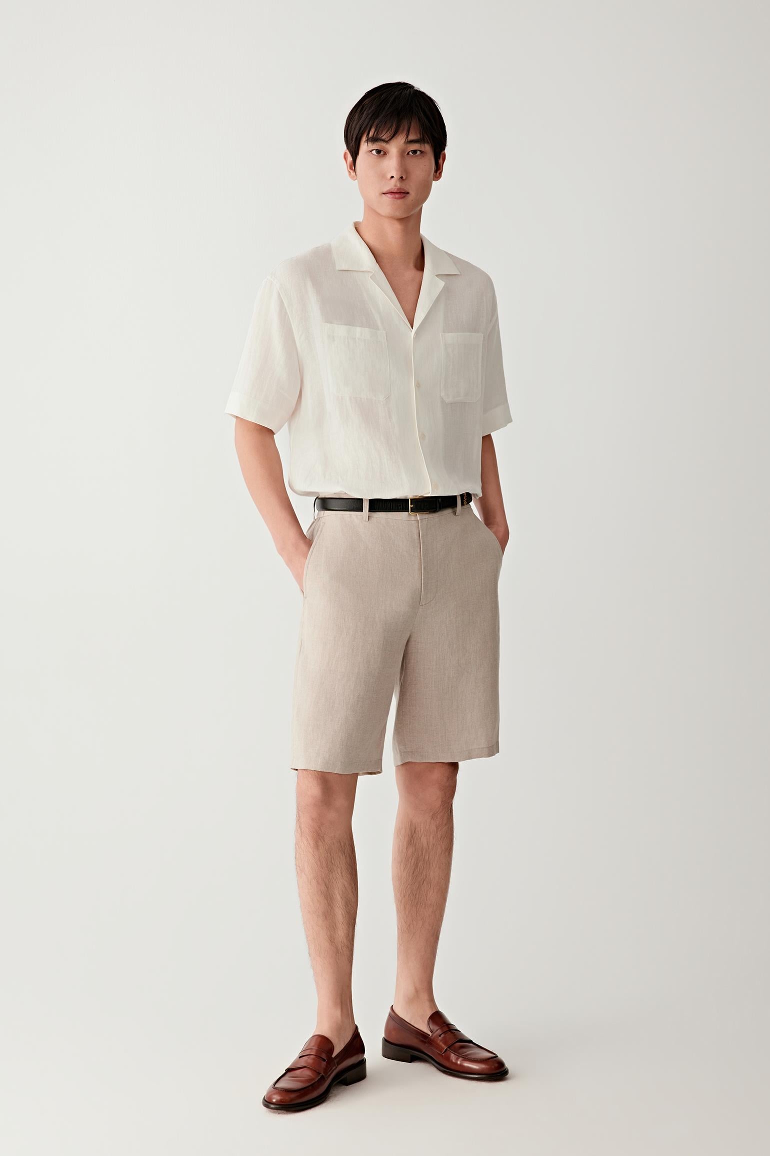 Full-length view showing the shirt paired with coordinating shorts. The image emphasizes the fluid drape, open collar construction and easy proportions of the garment, illustrating its relaxed warm-weather character.