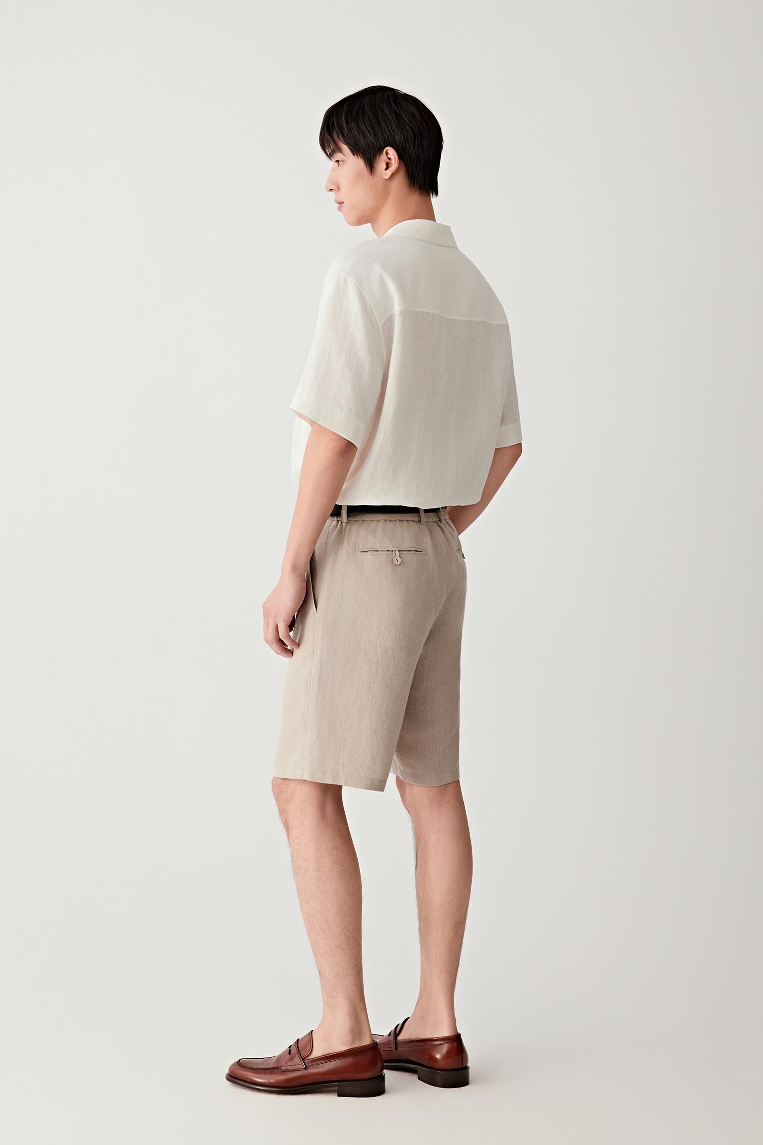 Side view highlighting the straight cut, short sleeves and lightweight drape of the linen fabric. The image shows how the garment falls naturally away from the body while maintaining clean lines.