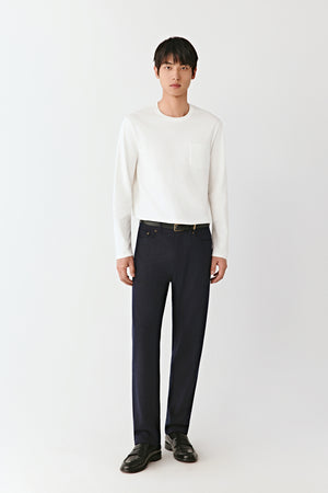 Full-length front view of a man wearing navy wool jersey trousers paired with an ivory sweater, presenting a relaxed yet elegant silhouette.