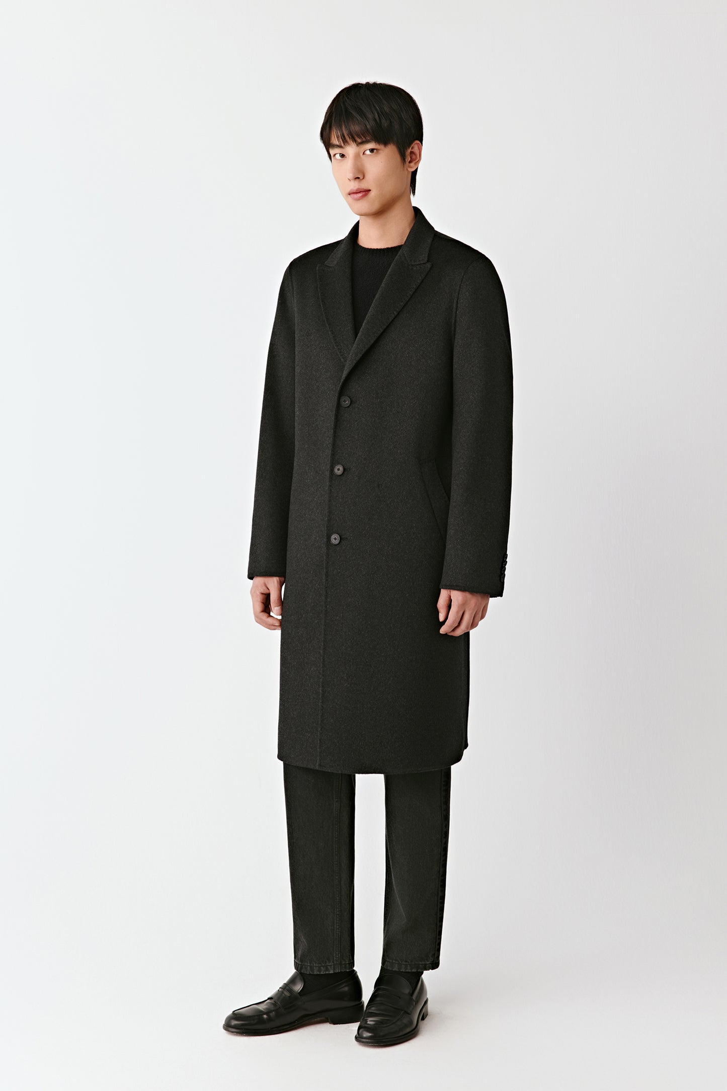 Man wearing a black overcoat on a white background