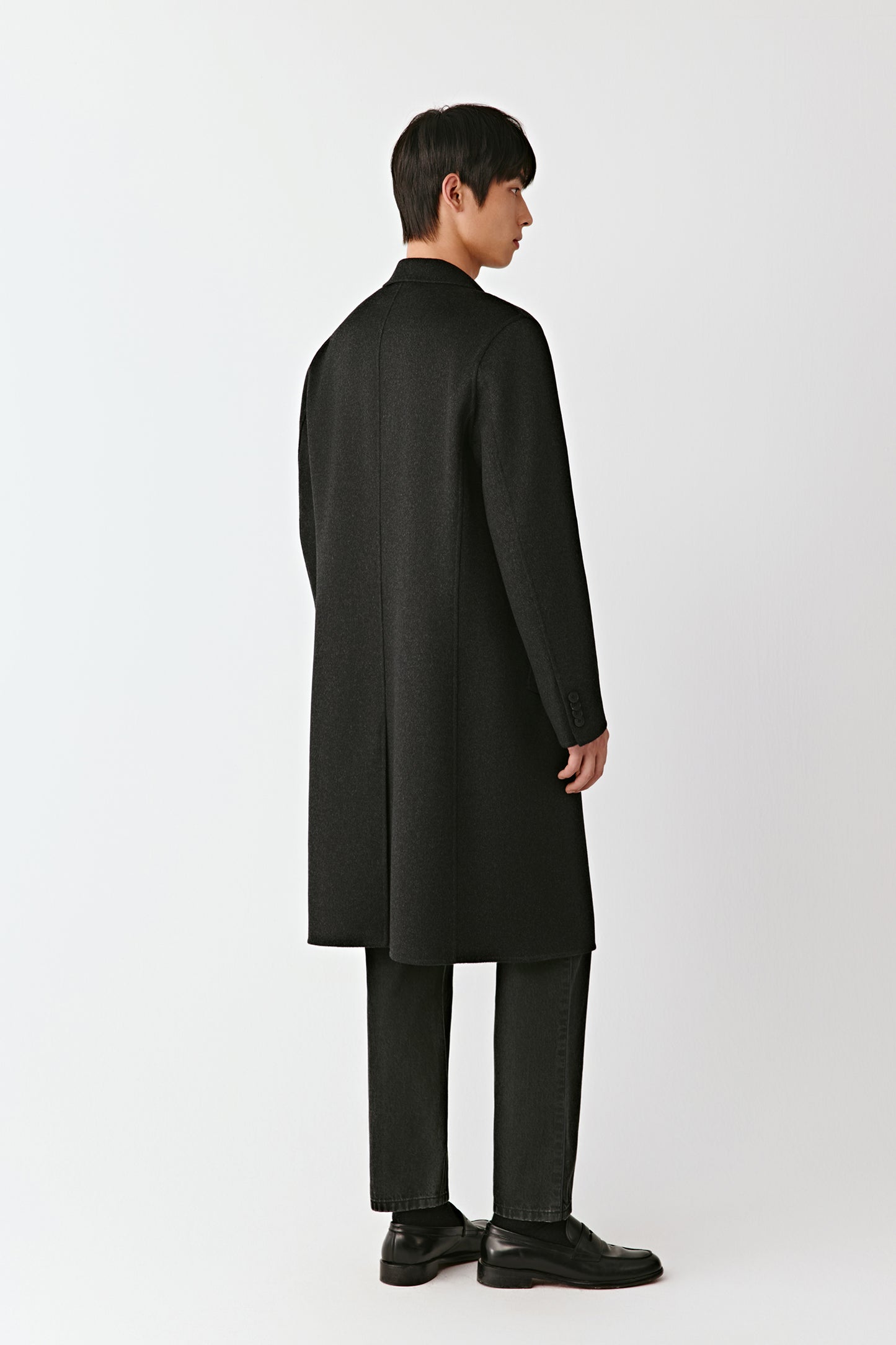 Man wearing a black overcoat on a white background