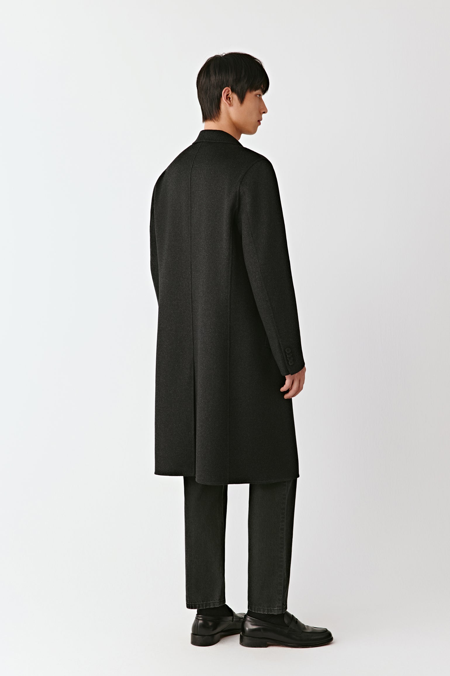 Man wearing a black overcoat on a white background