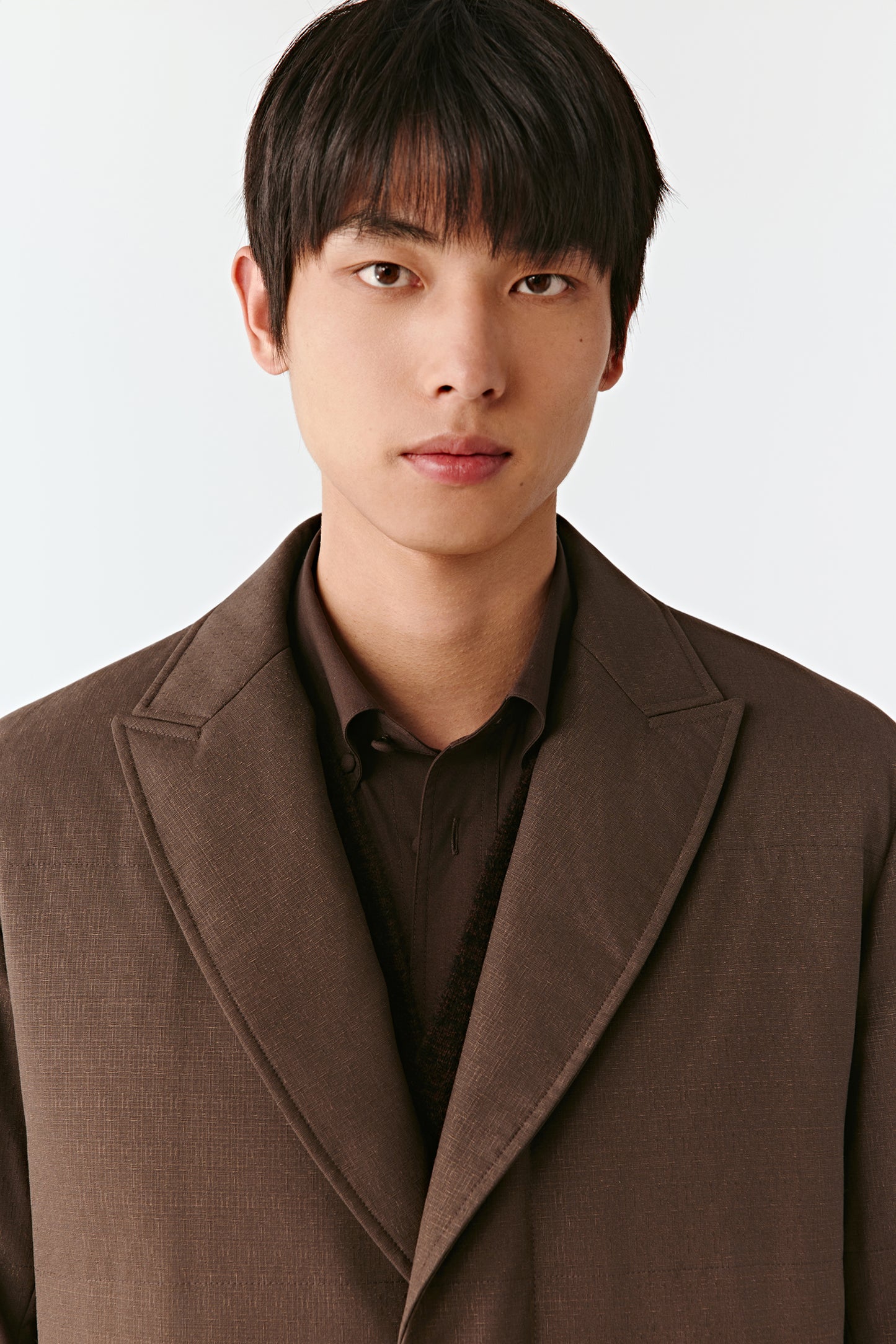 Man wearing a brown coat against a white background