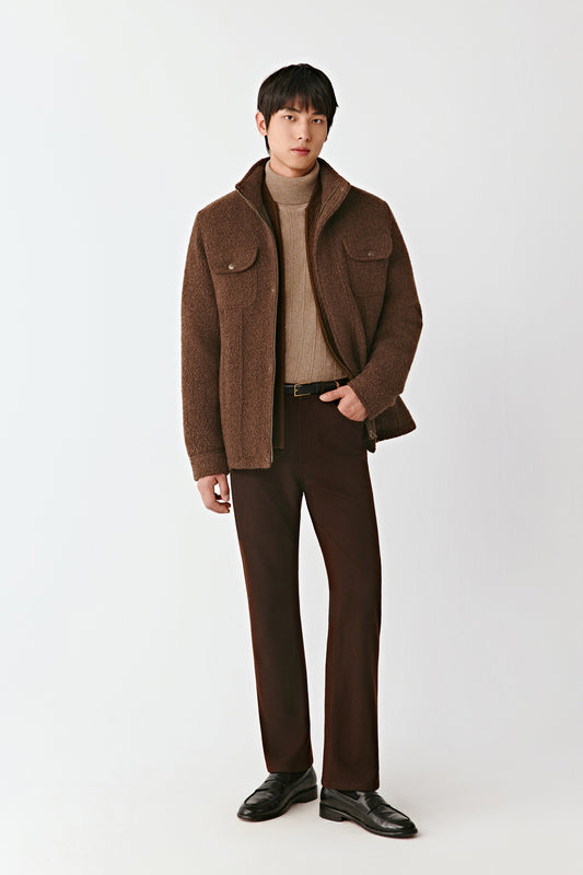 Man wearing a brown coat, turtleneck, and pants on a white background