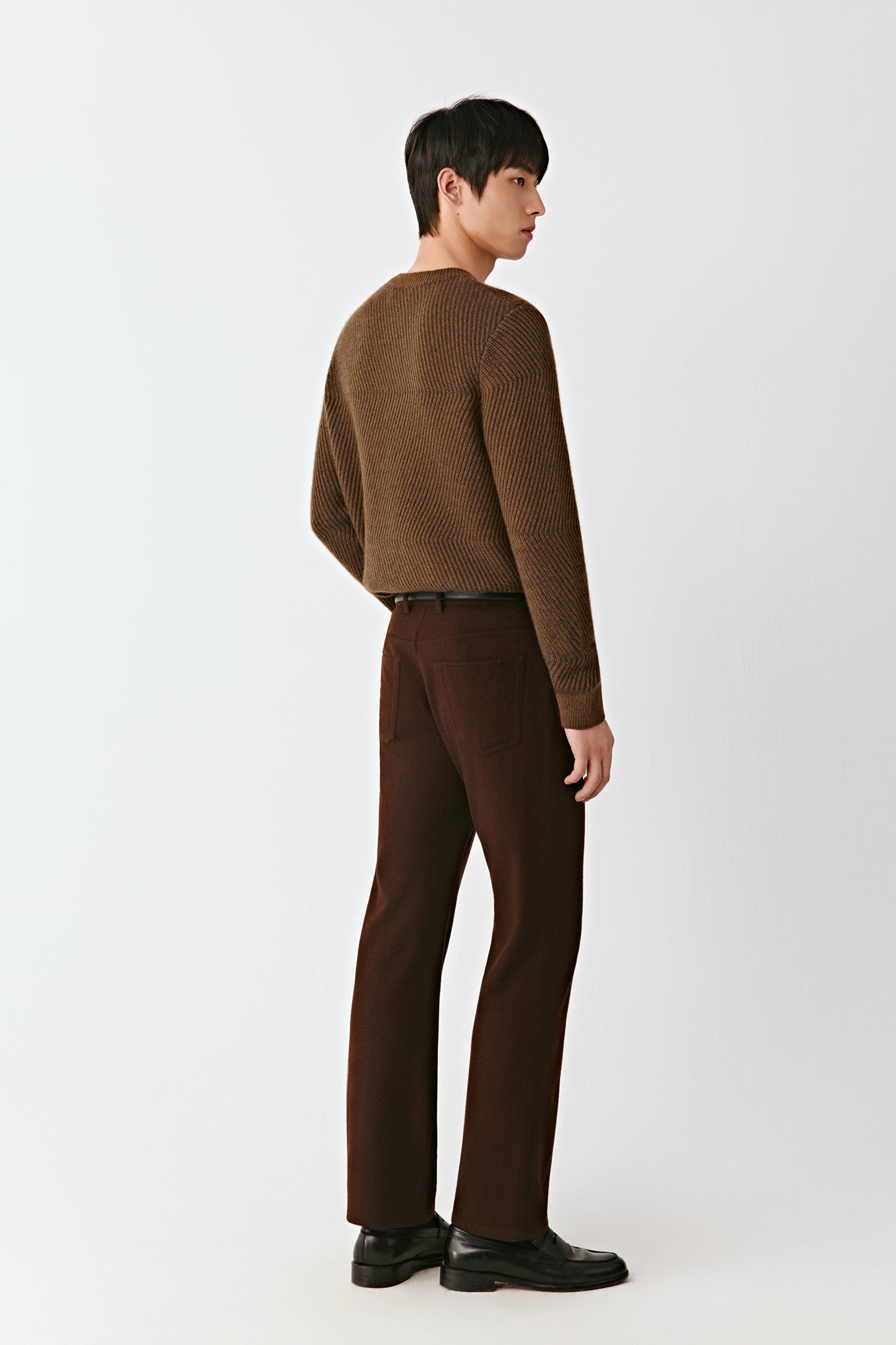 Person wearing a brown sweater and pants on a white background