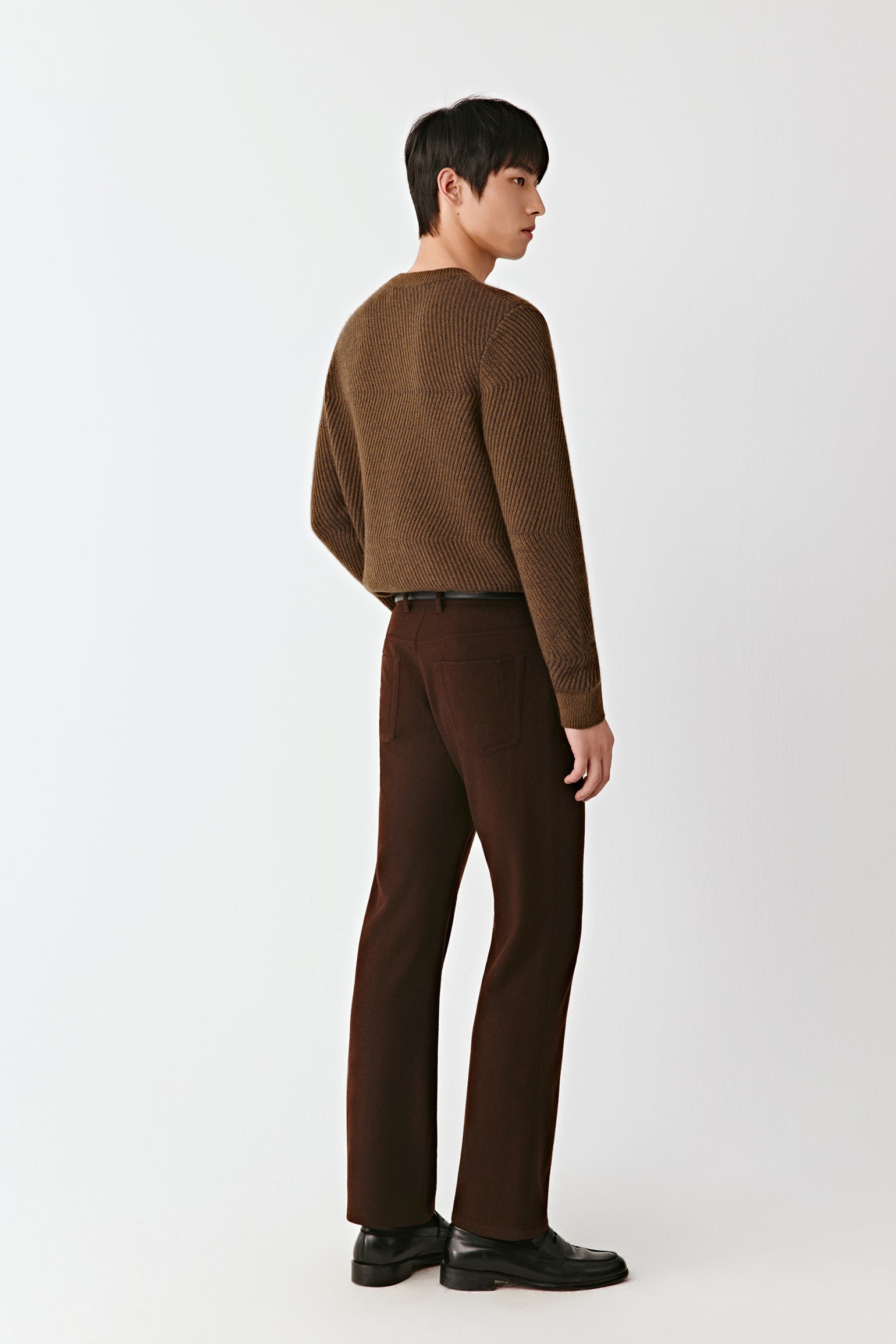 Person wearing a brown sweater and pants on a white background