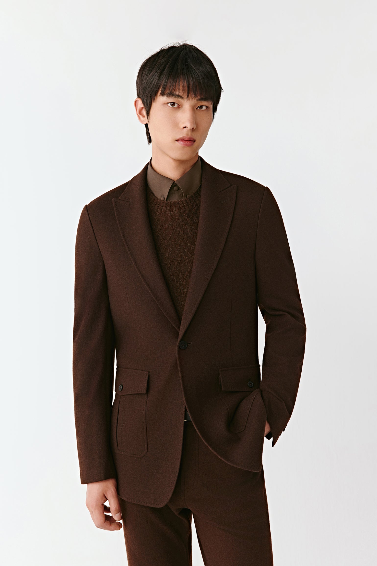 Man wearing a brown suit against a white background