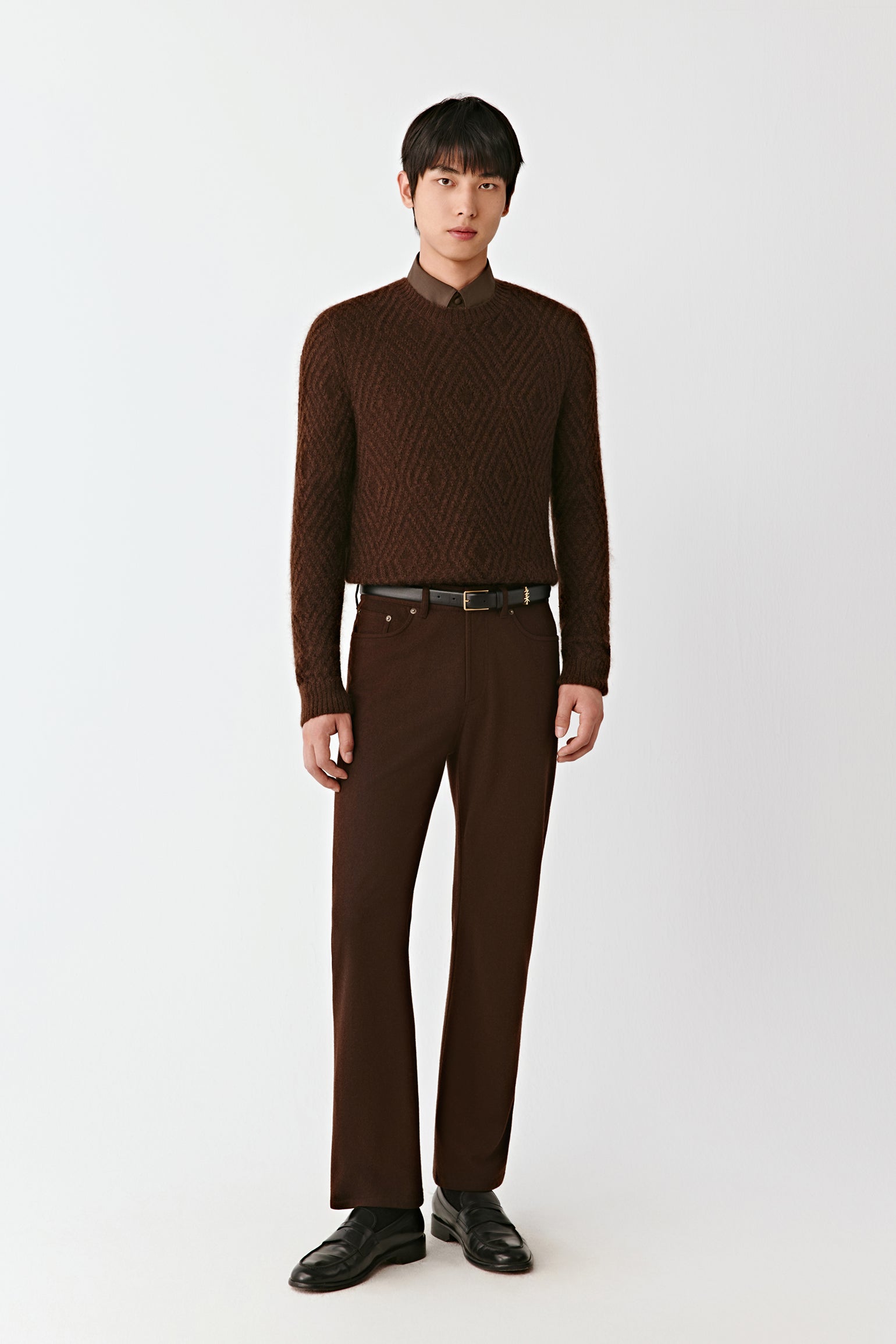 Man wearing a brown patterned sweater and pants on a white background