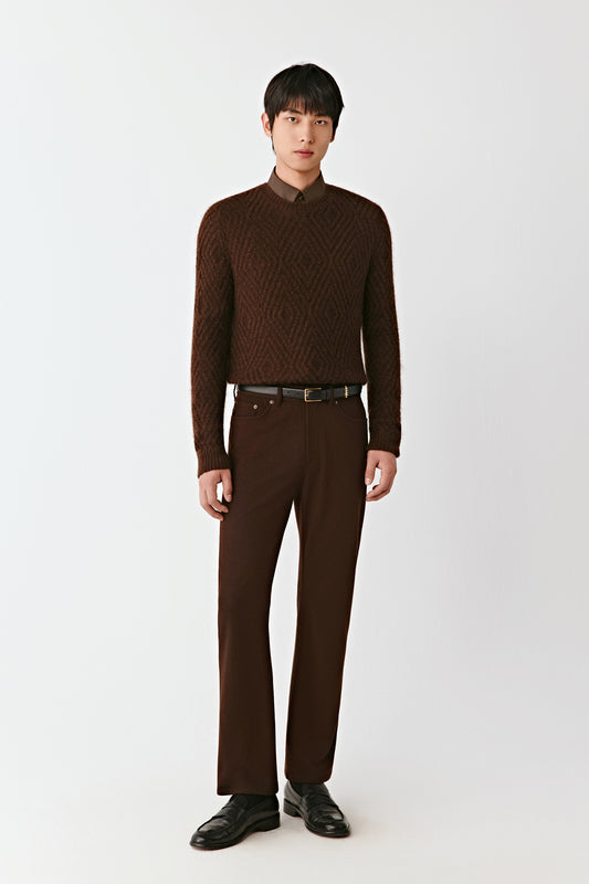 Man wearing a brown patterned sweater and pants on a white background