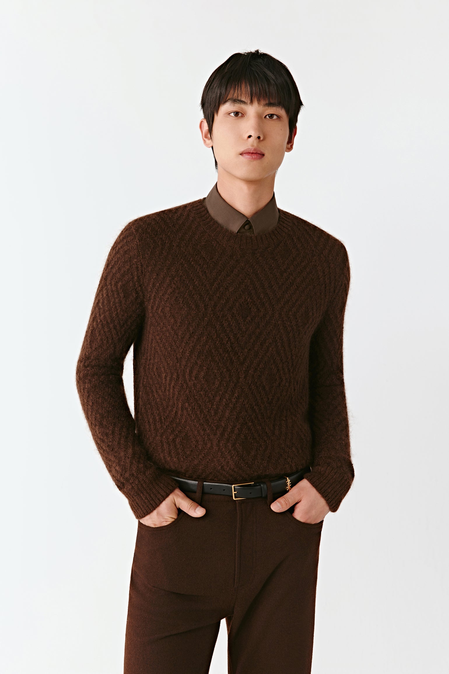 Man wearing a brown sweater and pants on a white background
